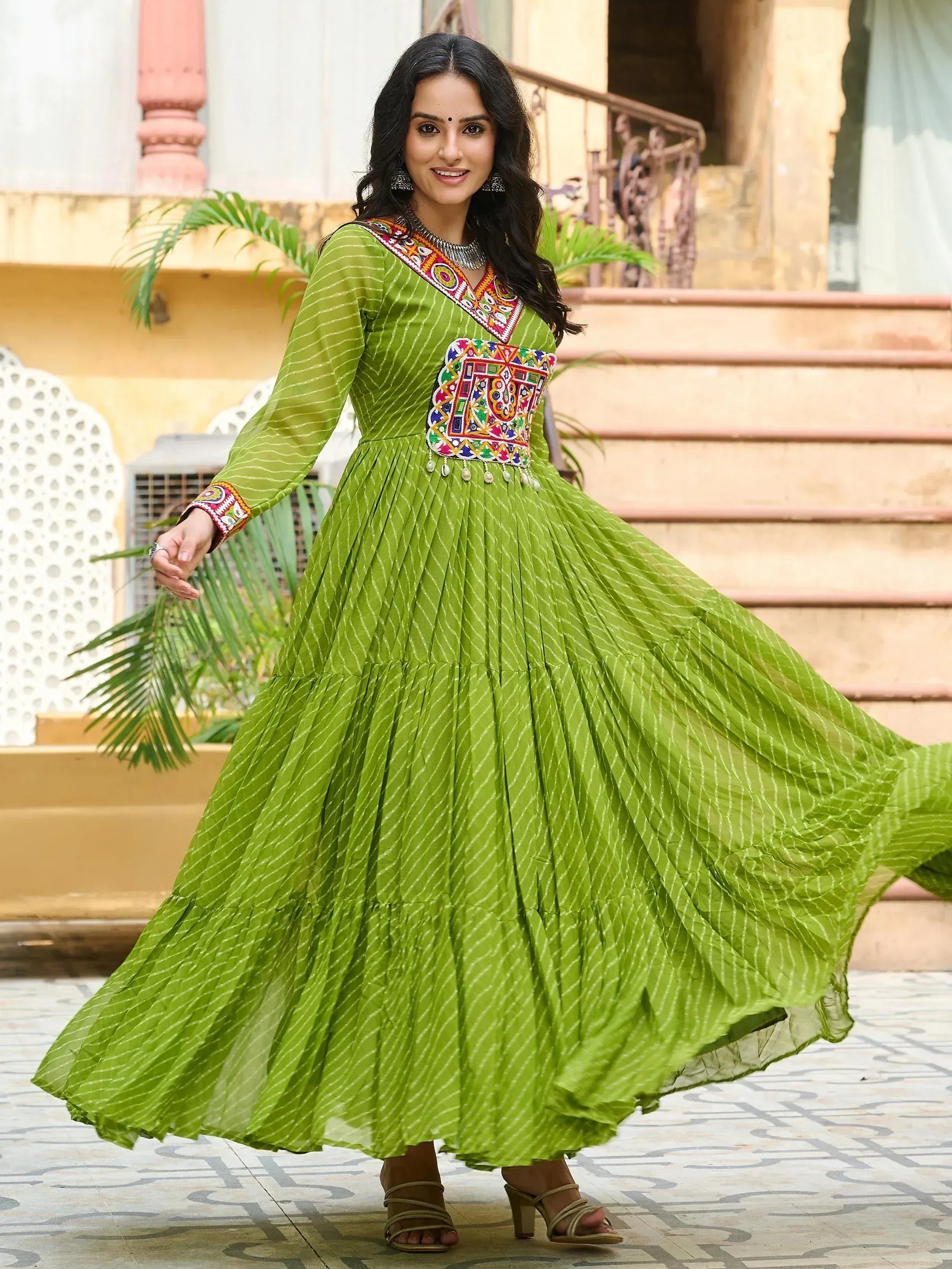 Green ethnic gown with colorful mirror work and pleated skirt, perfect for Indian occasions
