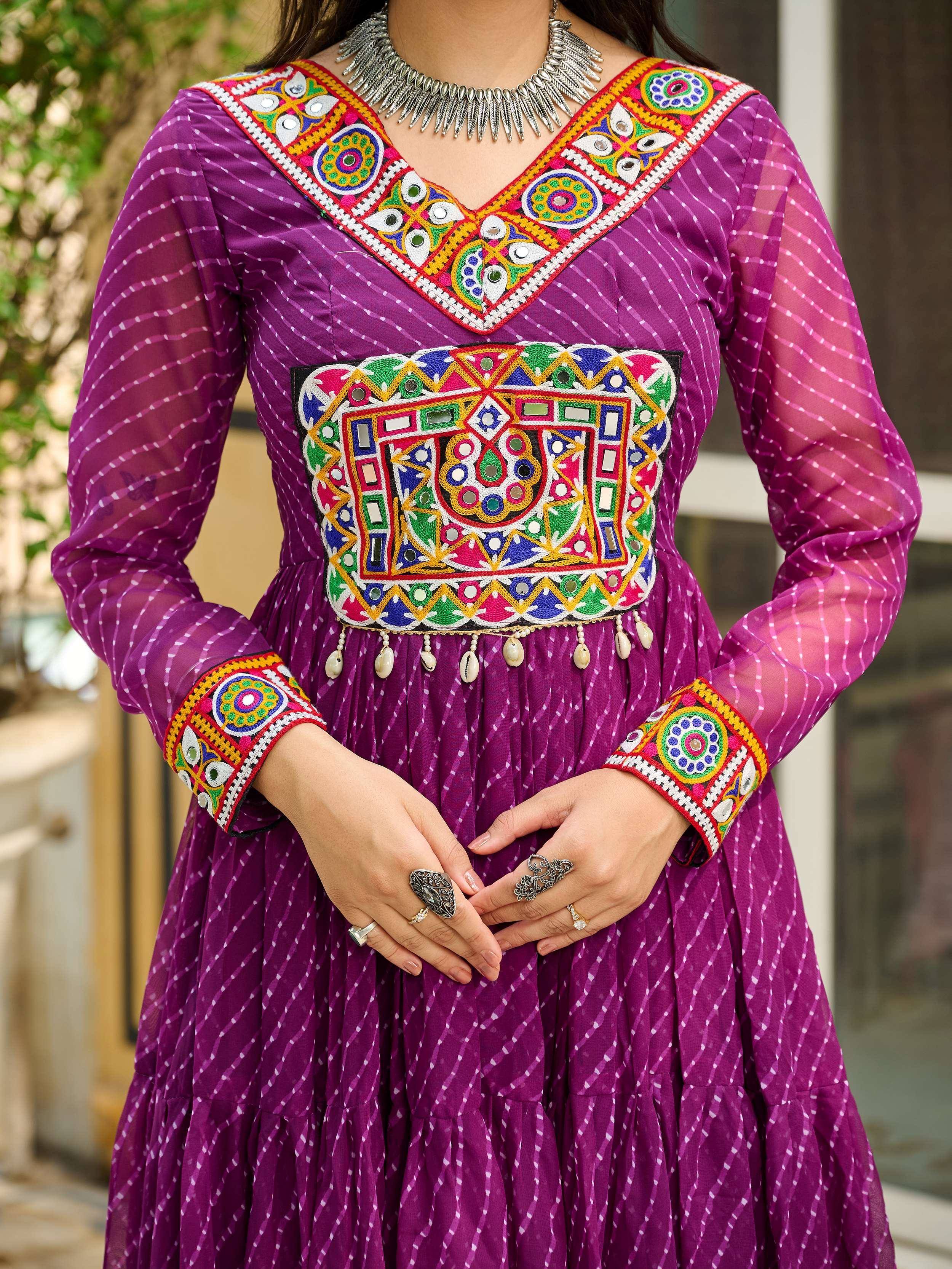 Purple ethnic gown with vibrant mirror work, embroidery, and sheer sleeves, paired with statement jewelry.