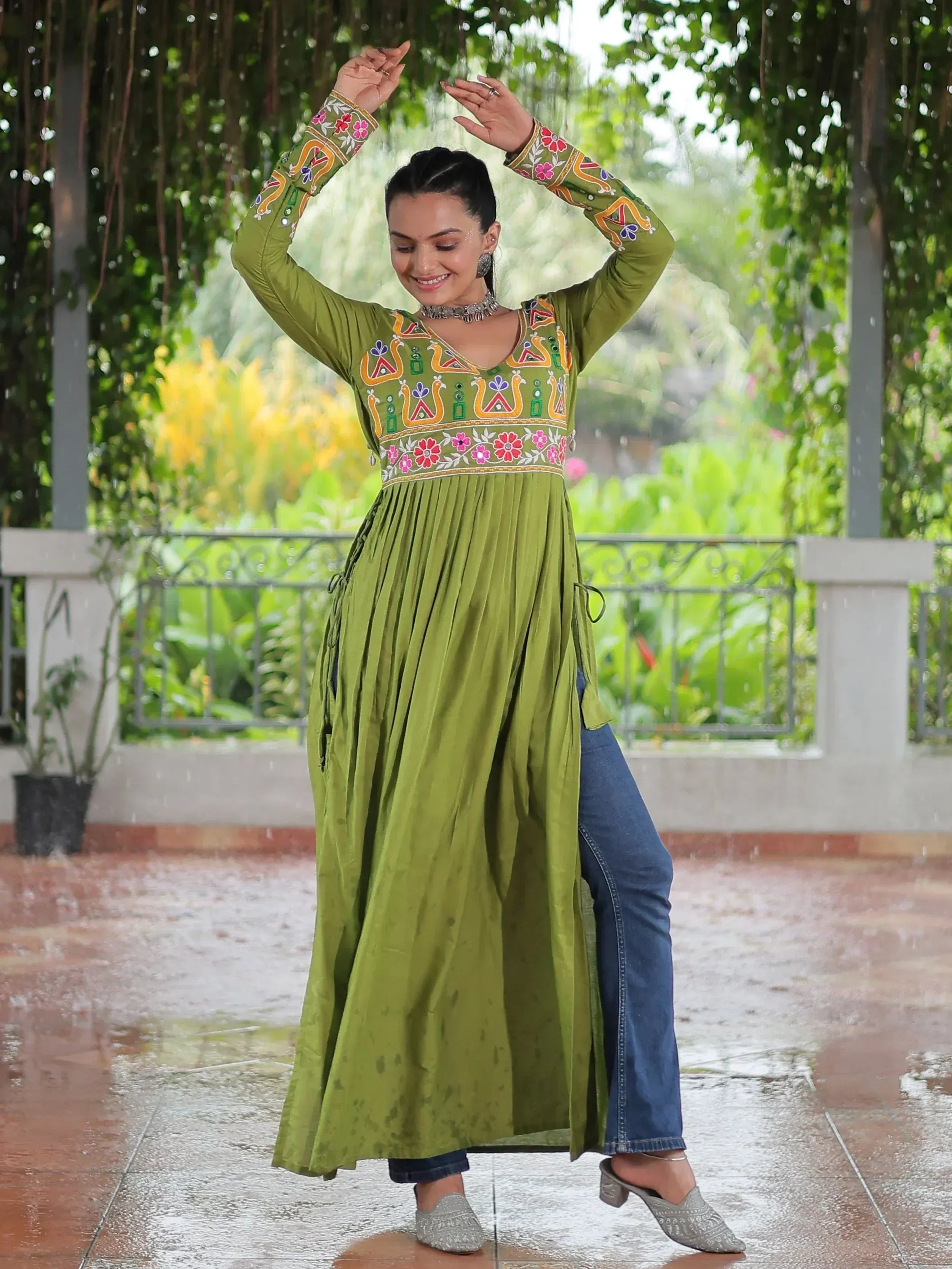Green embroidered ethnic kurti with floral motifs, paired with jeans, perfect for festive occasions.