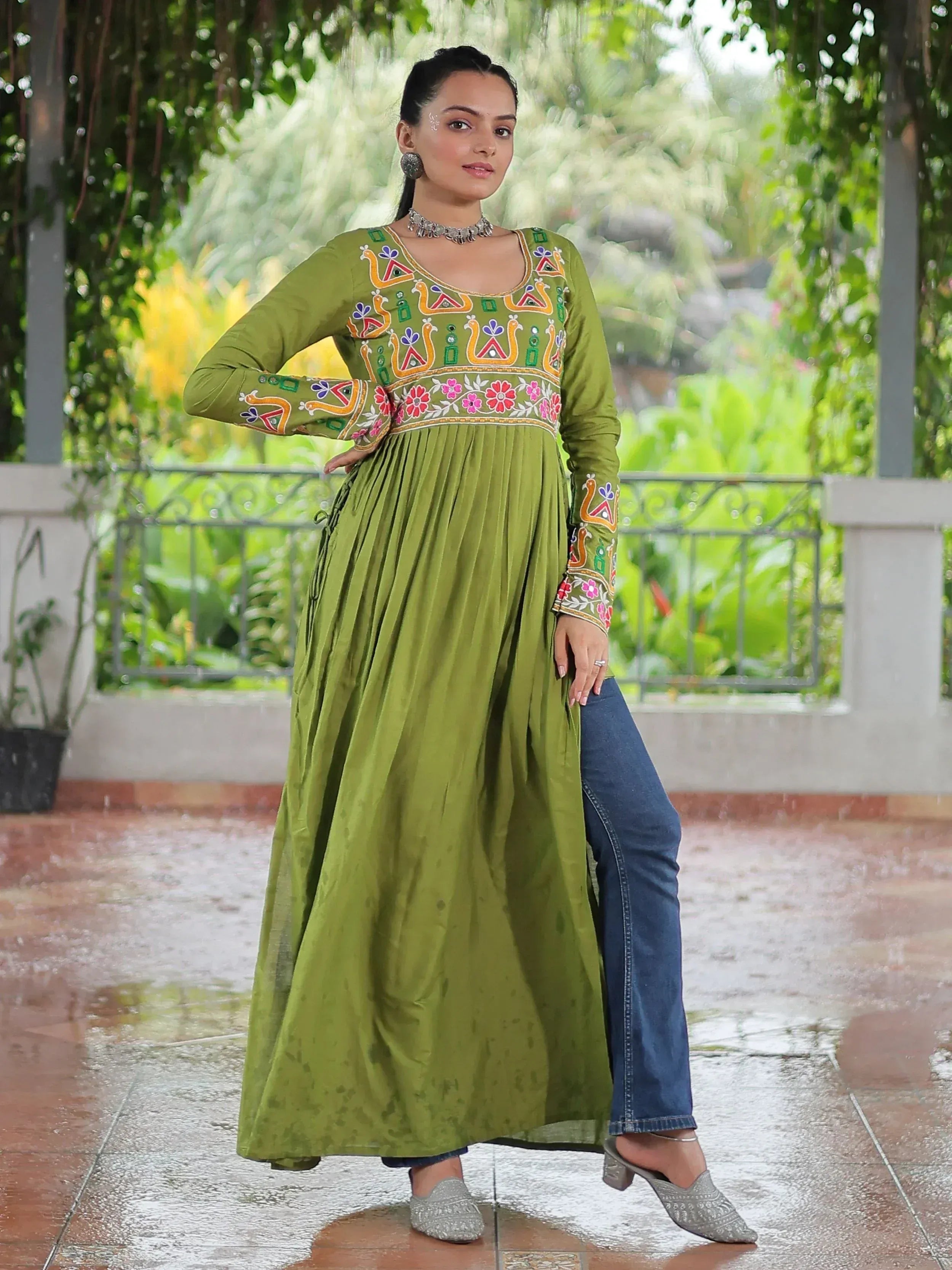 Olive green embroidered ethnic kurti with floral and peacock motifs, paired with jeans for a fusion look.