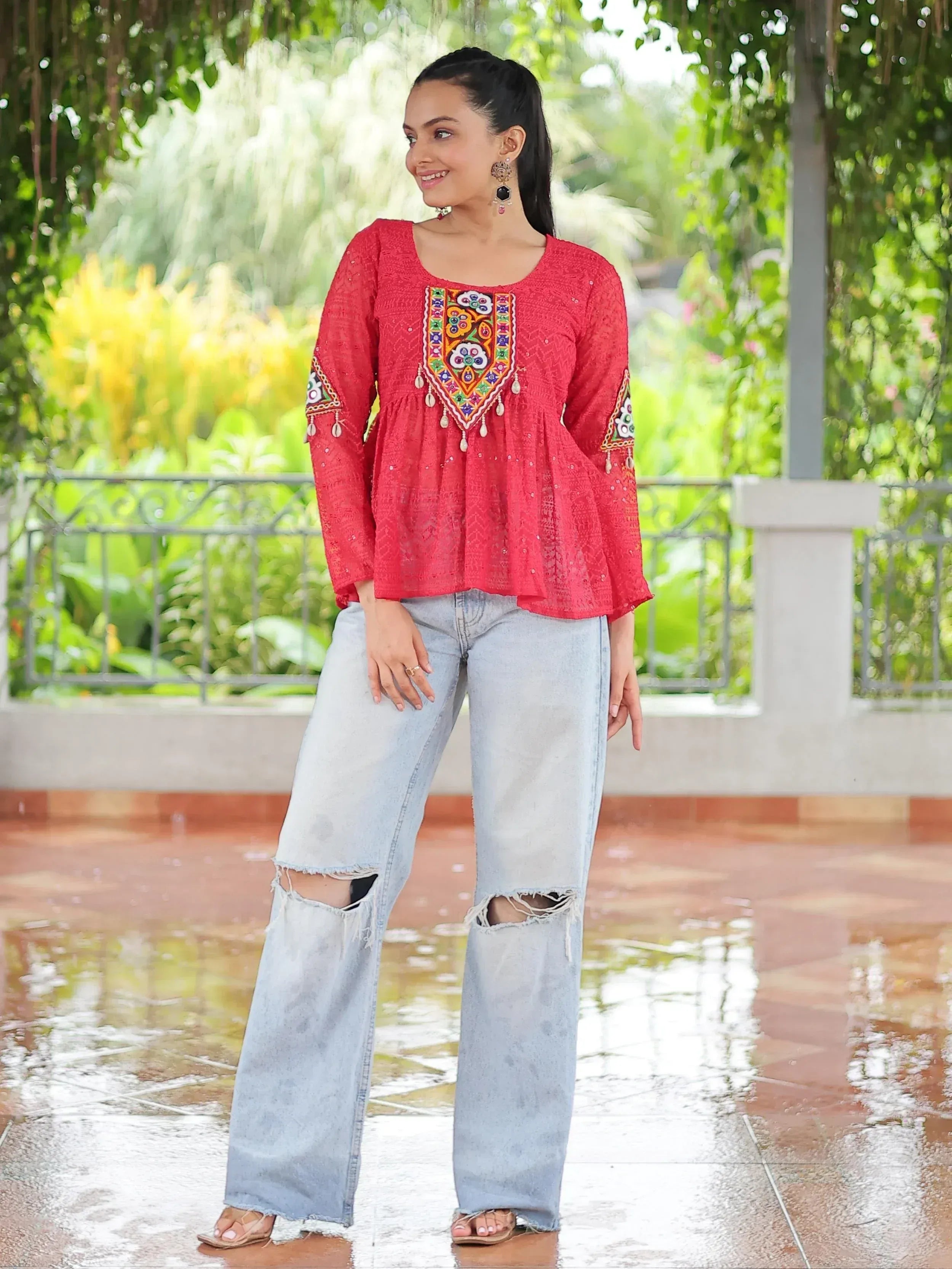 Red embroidered ethnic top with bell sleeves paired with ripped jeans, perfect for casual Indian wear