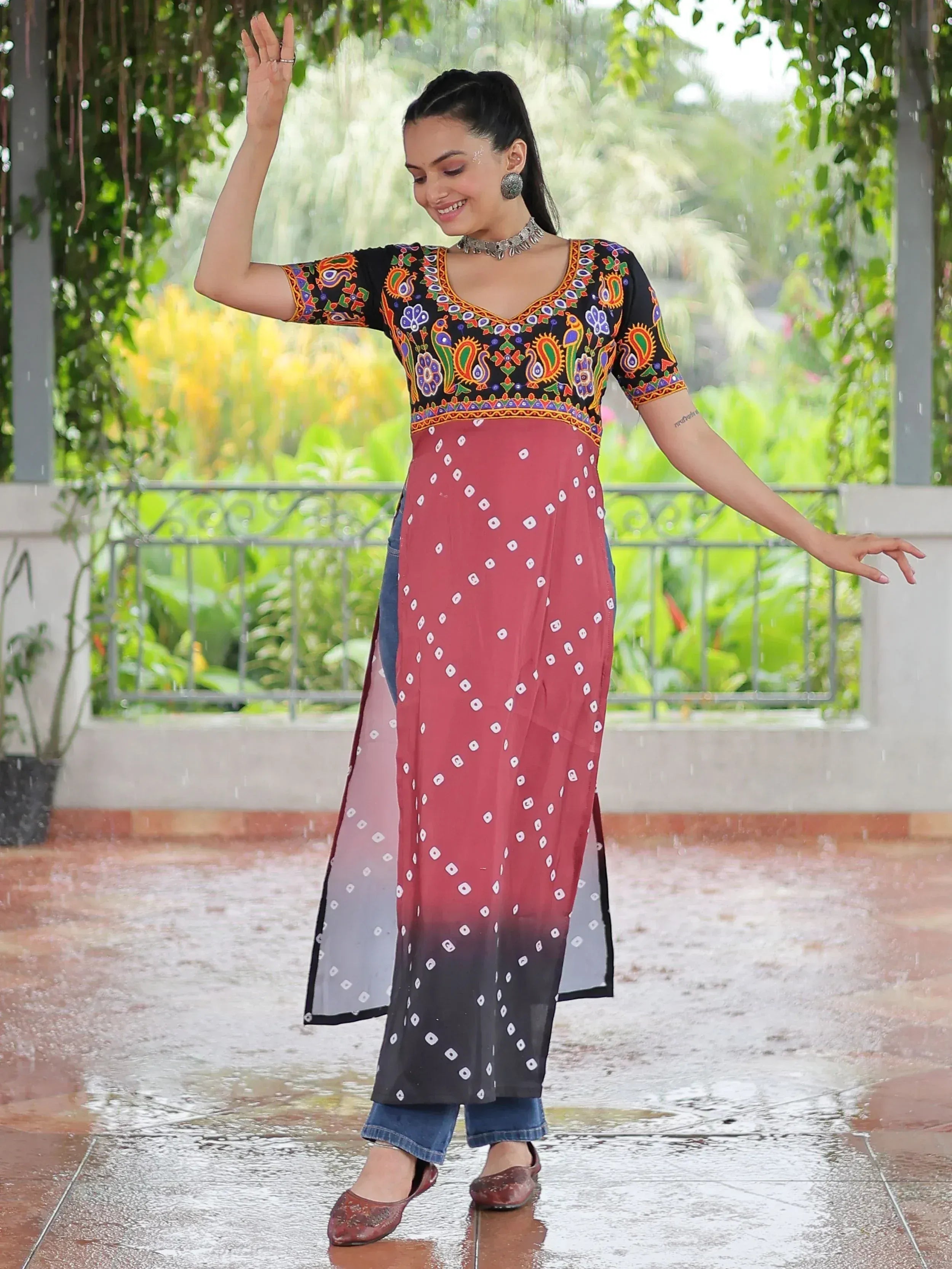 Woman in colorful embroidered kurta with ombre bandhani dupatta, dancing in rain, ethnic wear