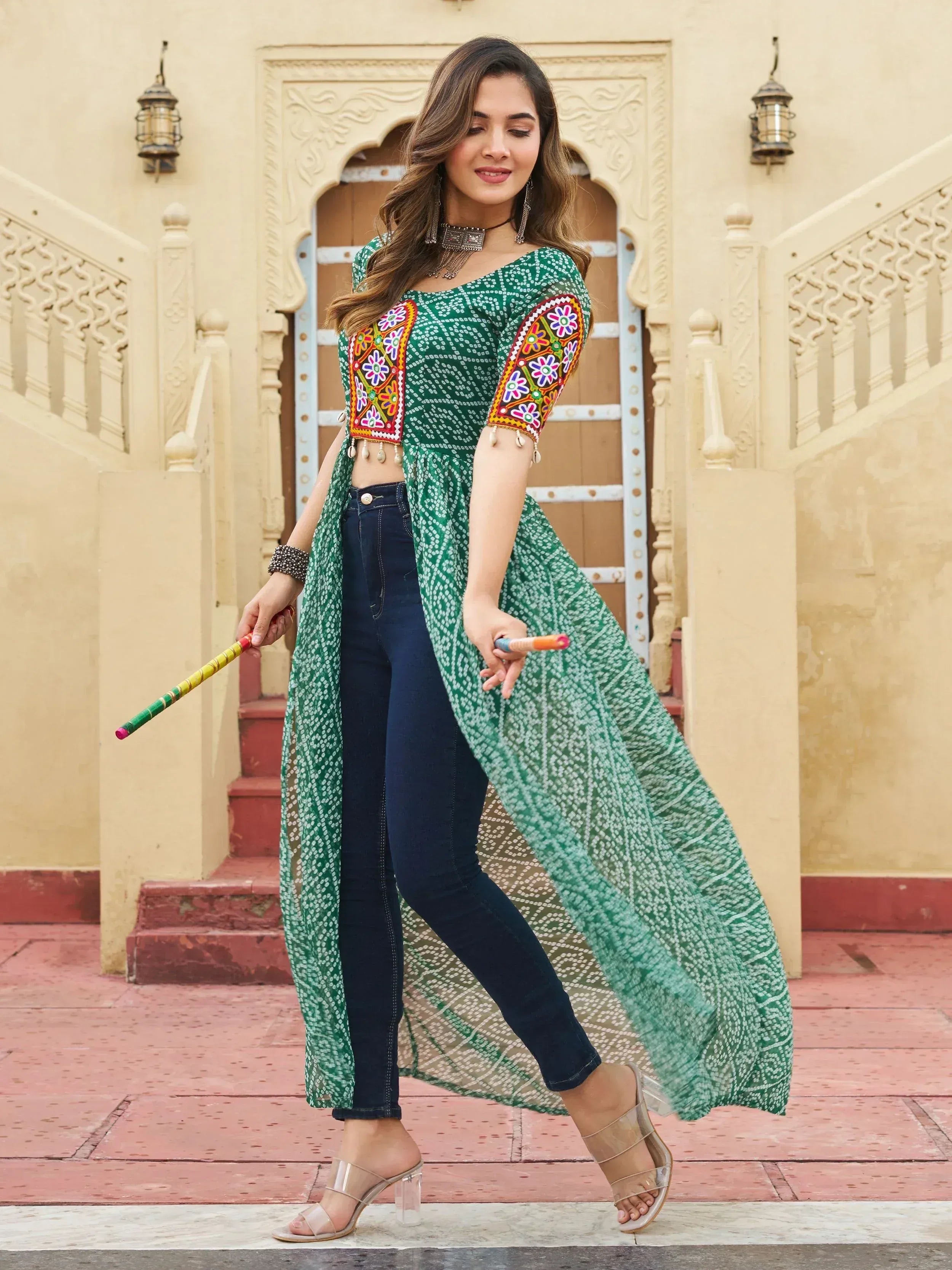 Green embroidered ethnic kurti with mirror work, paired with jeans, perfect for festive Indian wear.