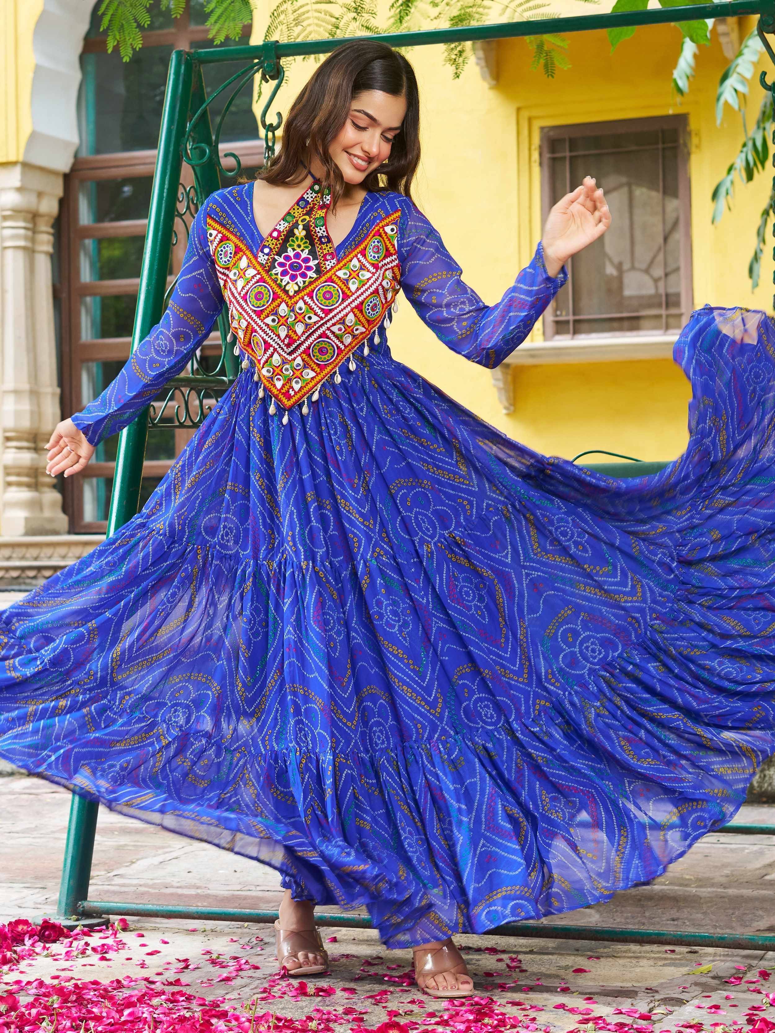 Woman twirling in vibrant blue ethnic gown with colorful mirror work, perfect for Indian occasions