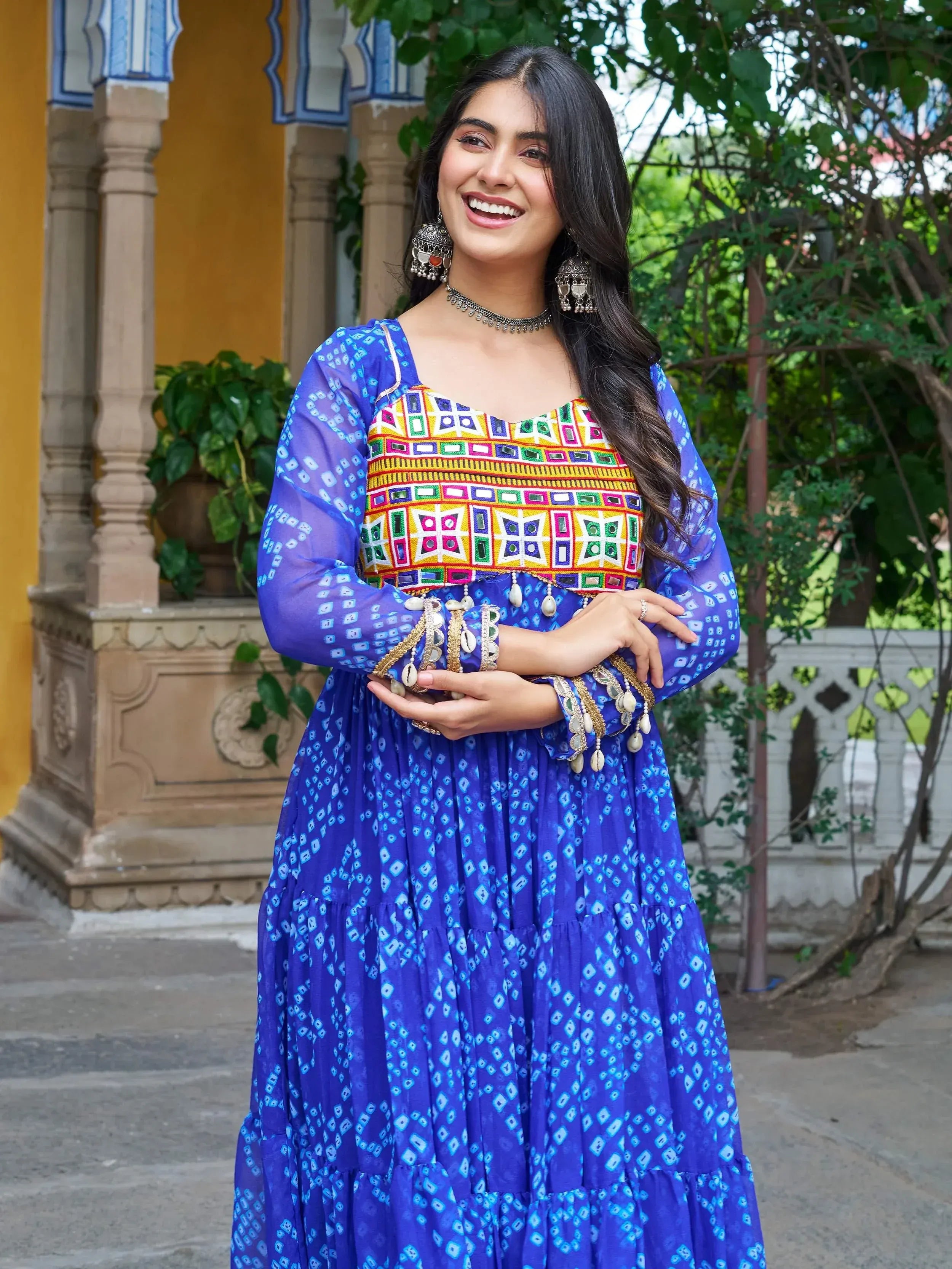 Woman in vibrant blue ethnic gown with colorful mirror work, perfect for Indian festivals and occasions