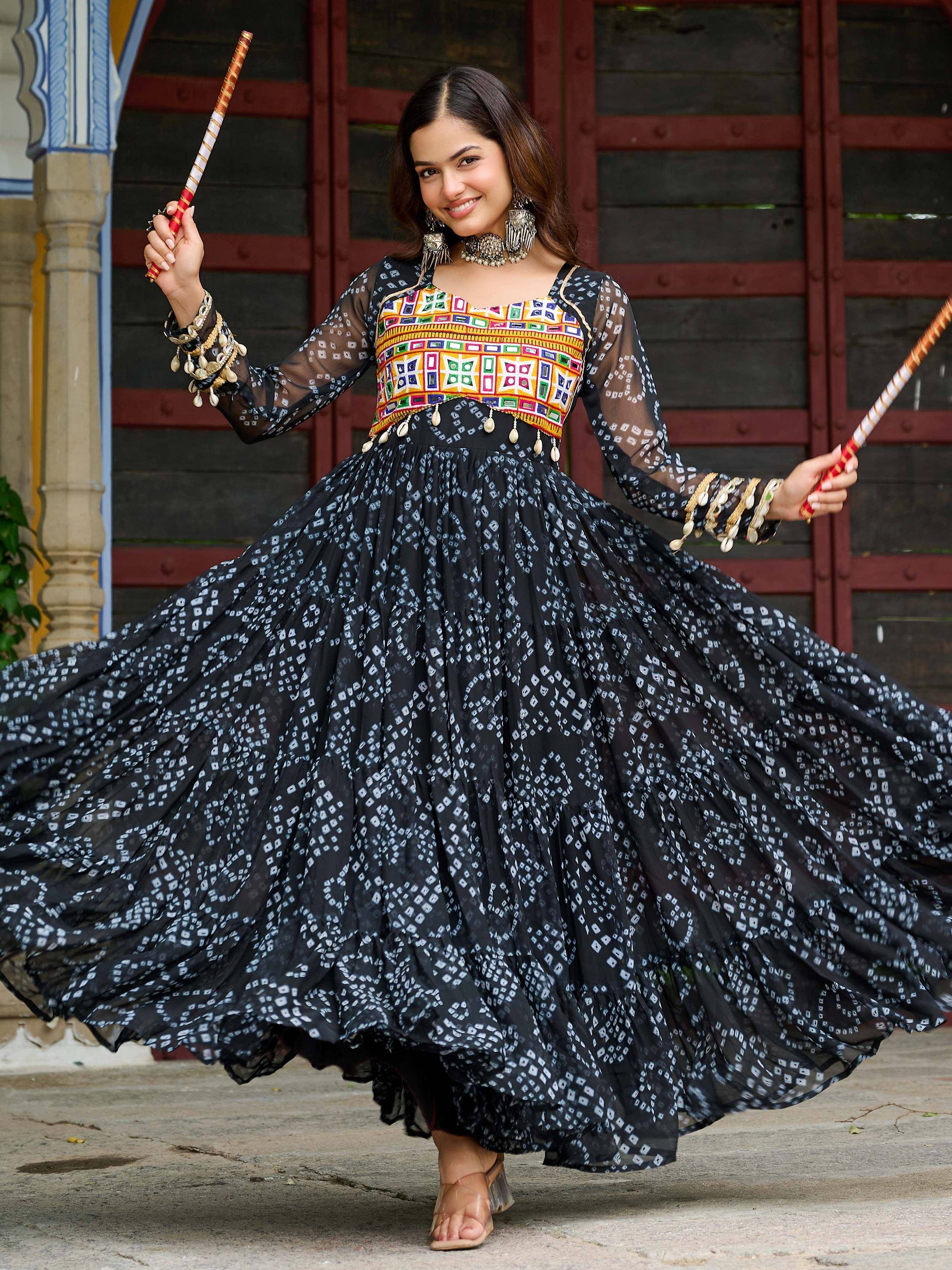 Woman in black printed ethnic gown with colorful embroidery, dancing with dandiya sticks