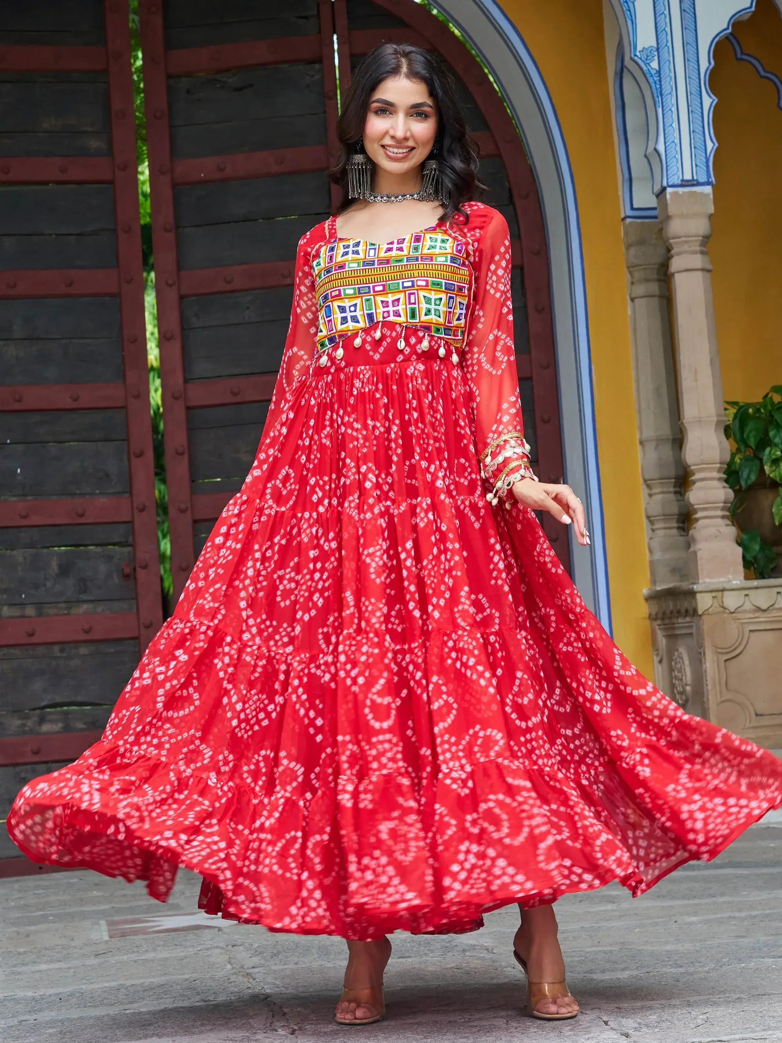 Red ethnic gown with colorful embroidery and tiered skirt, perfect for Indian festive wear