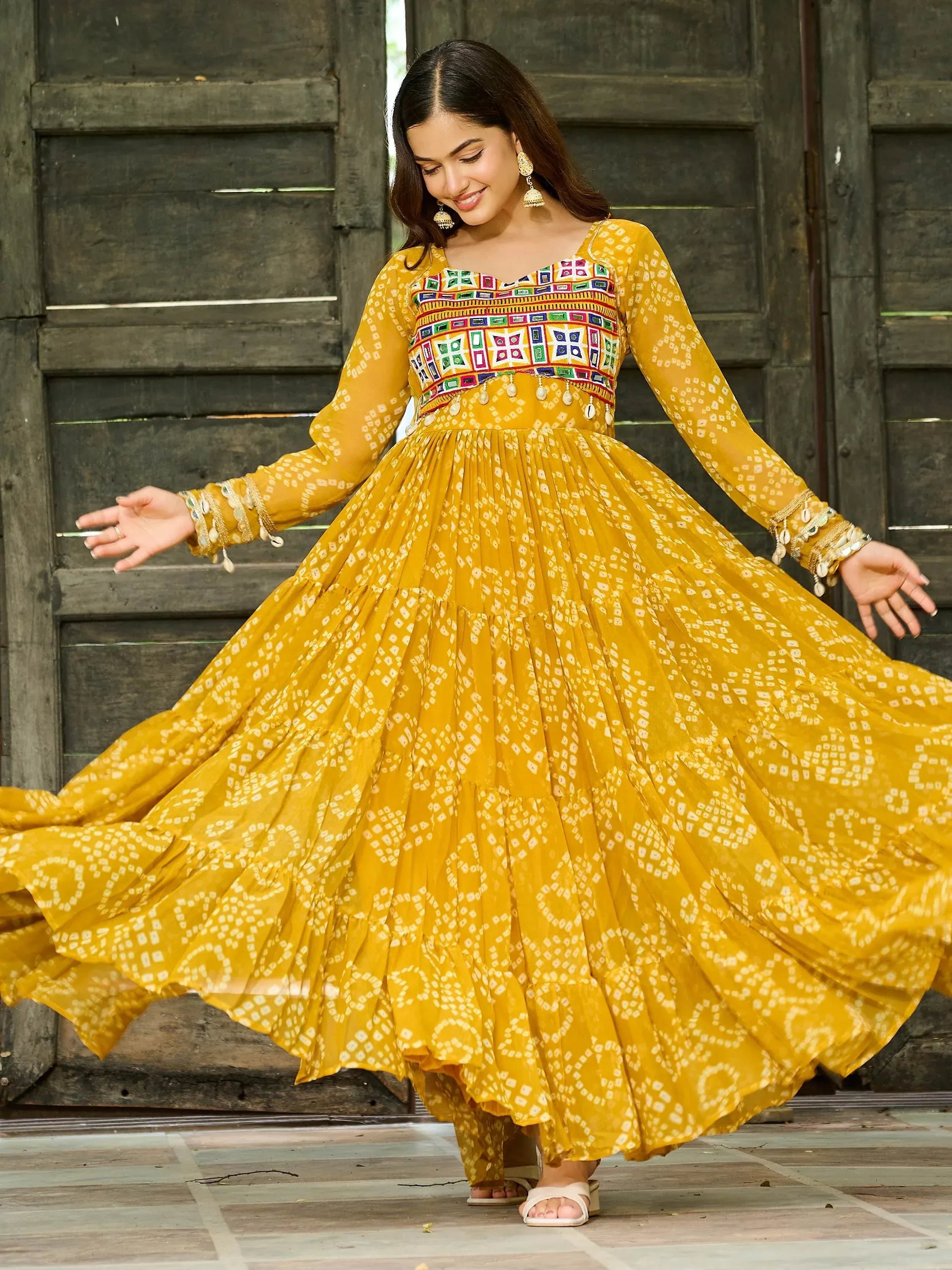 Yellow ethnic gown with mirror work and bandhani print, perfect for festive occasions