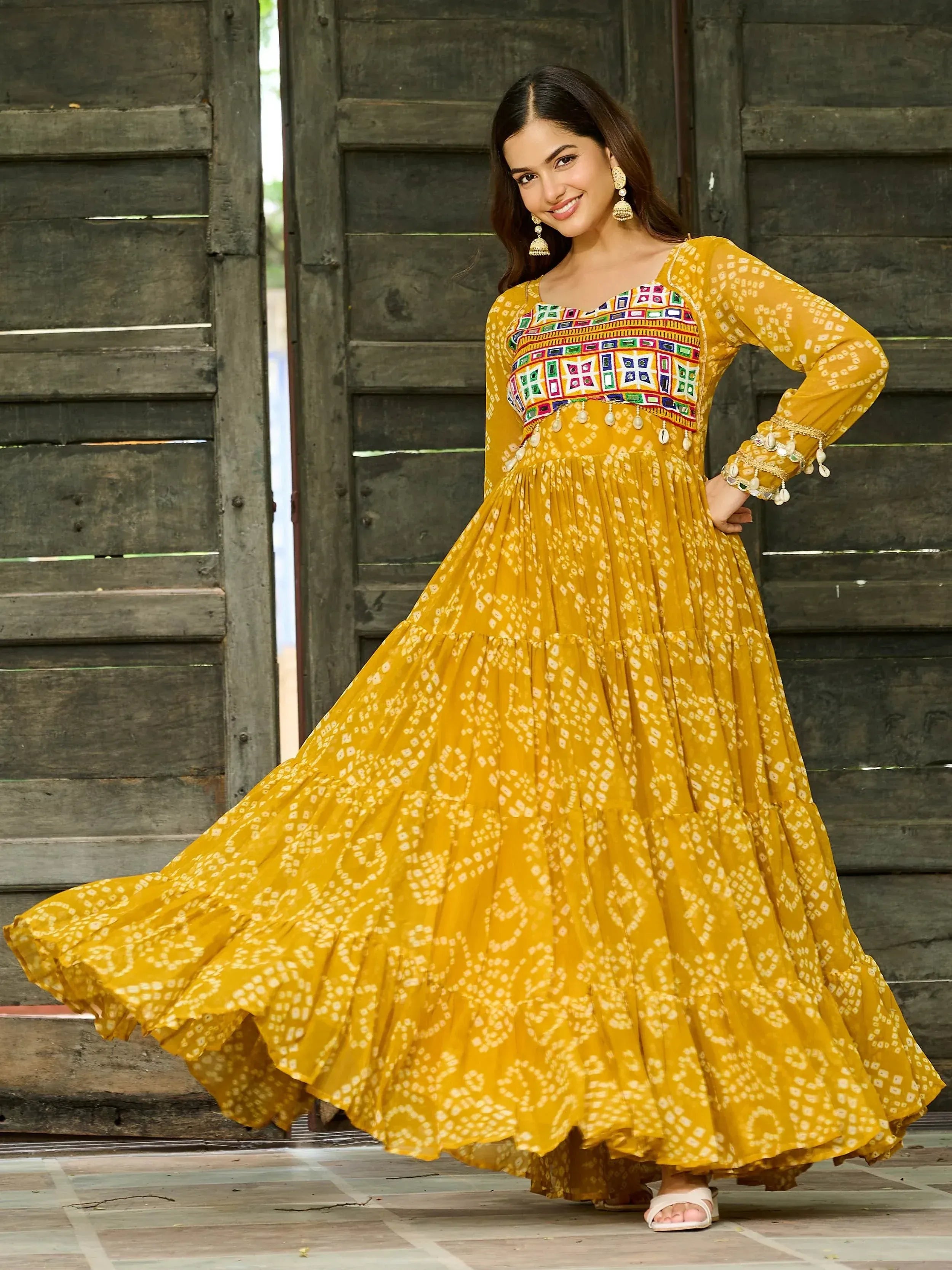 Yellow ethnic gown with mirror work and tiered skirt, perfect for Indian festive occasions