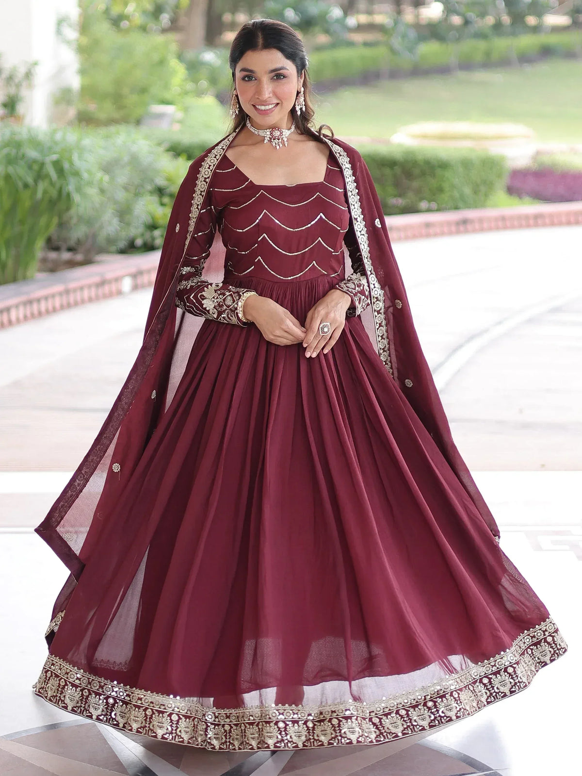 Maroon ethnic gown with gold embroidery and scalloped detailing, perfect for Indian celebrations