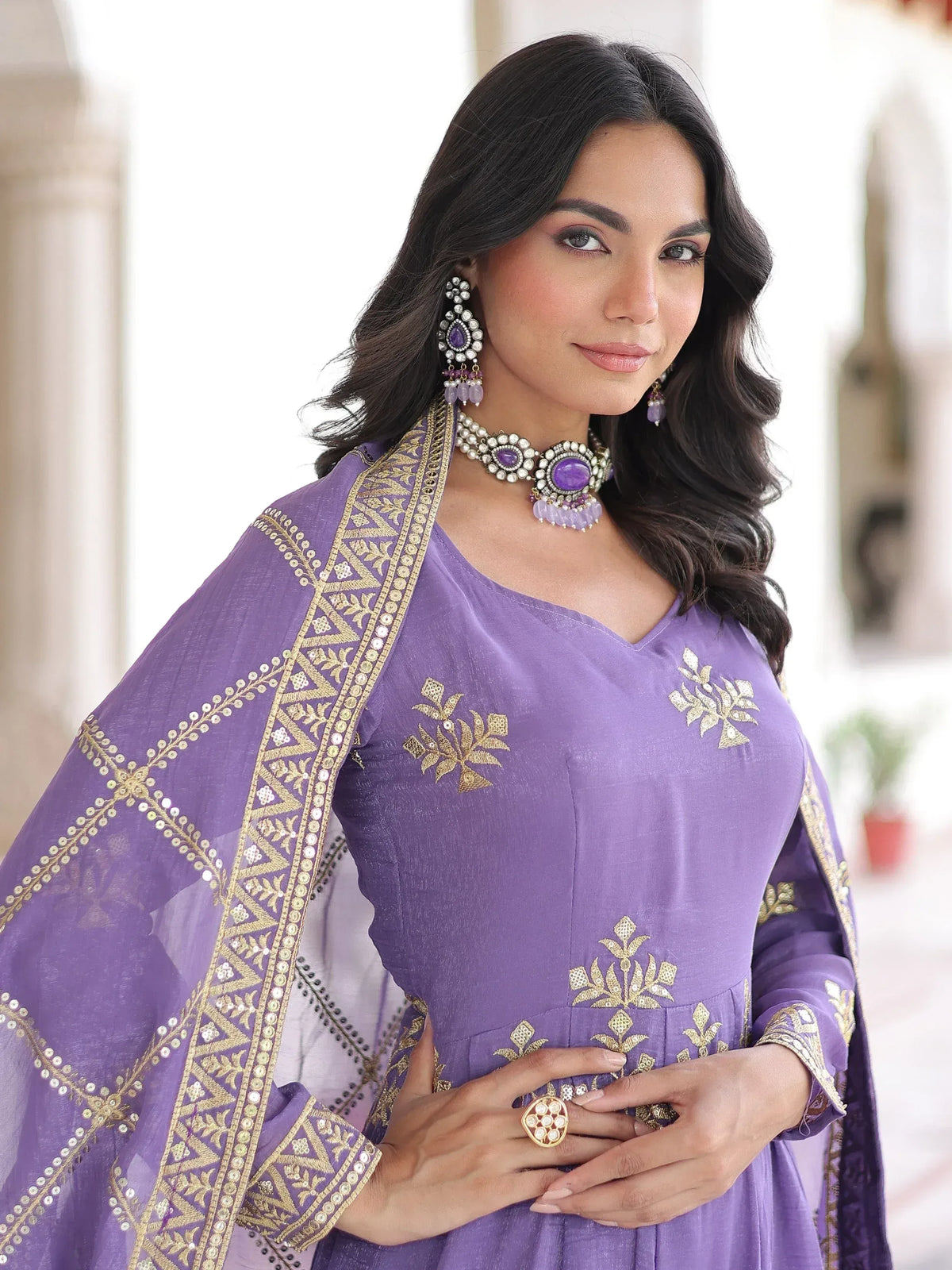 Purple ethnic gown with gold embroidery and matching dupatta, styled with traditional jewelry for Indian wear.
