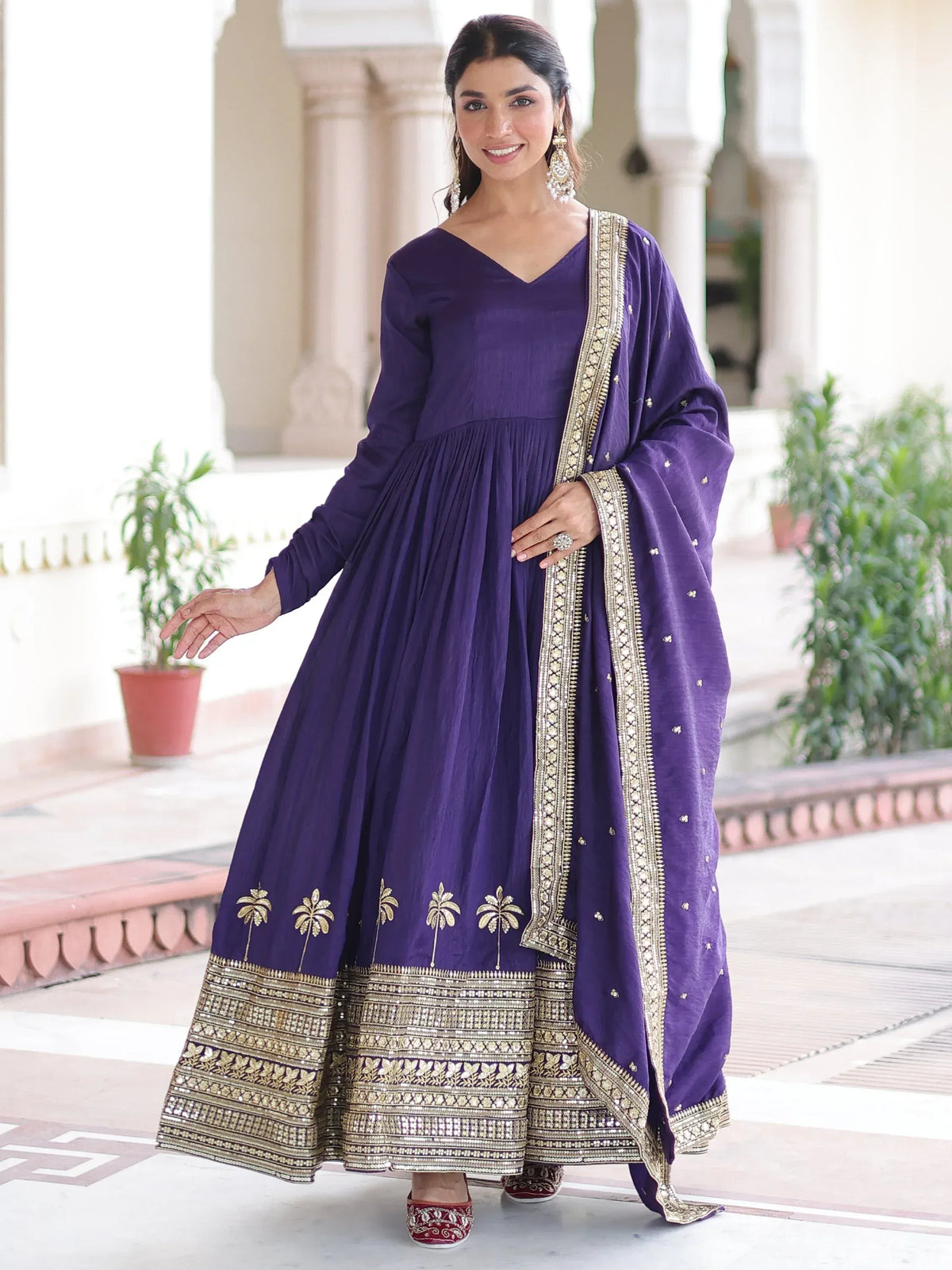 Woman wearing a purple Anarkali salwar kameez with gold embroidery and matching dupatta