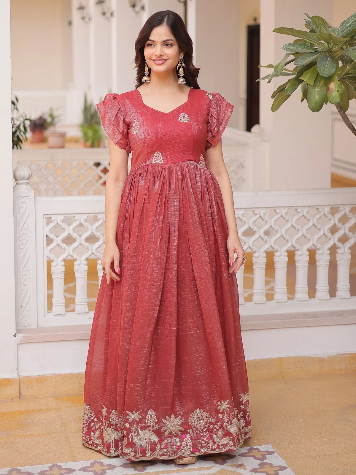 Woman wearing a dusty rose ethnic gown with gold embroidery and flutter sleeves