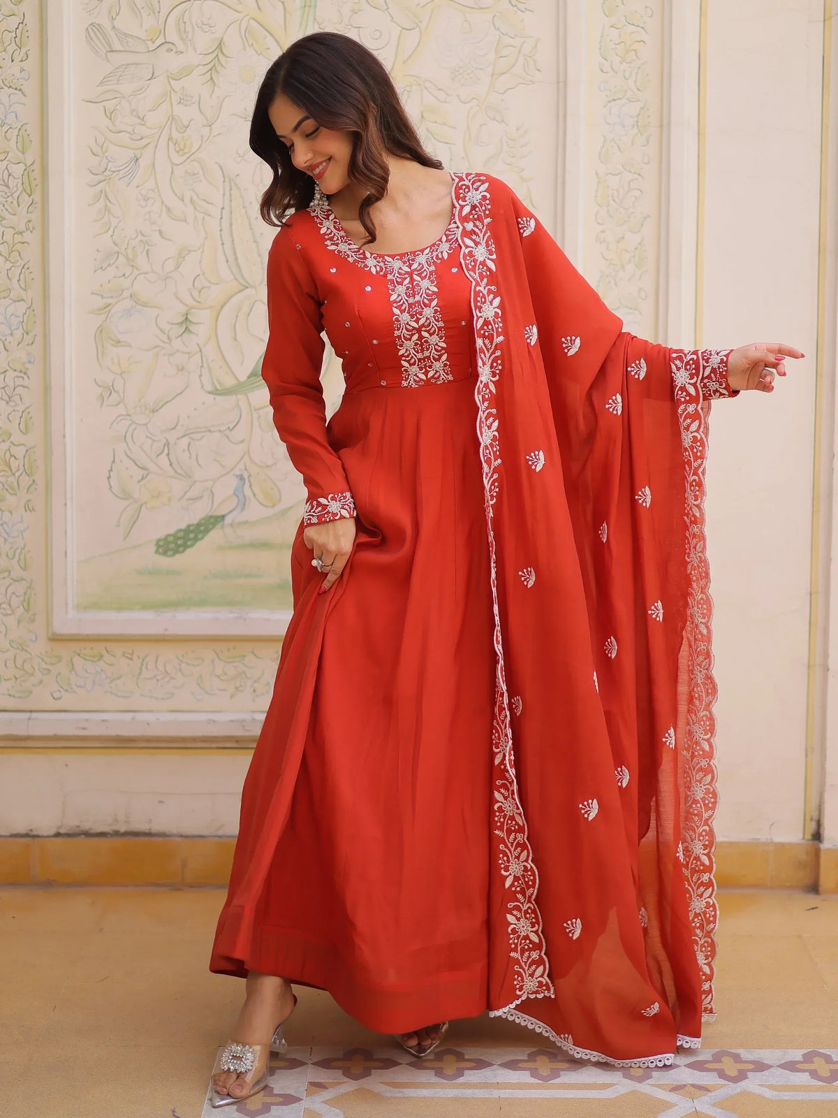 Woman wearing a red designer Anarkali suit with white embroidery and matching dupatta
