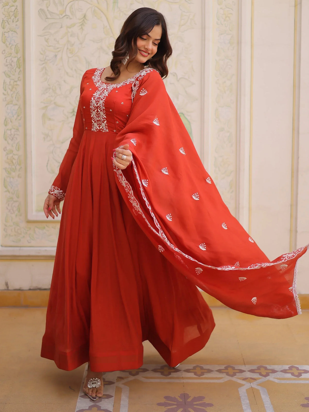 Woman wearing a red Anarkali suit with white embroidery and a matching dupatta.