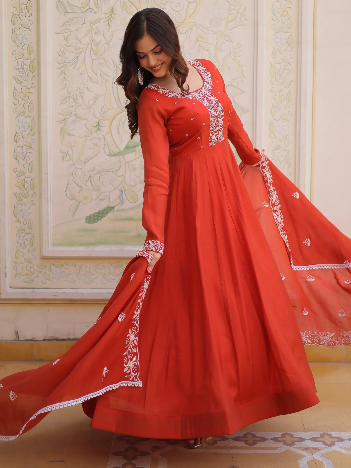 Woman wearing a red Anarkali ethnic gown with white floral embroidery and matching dupatta.