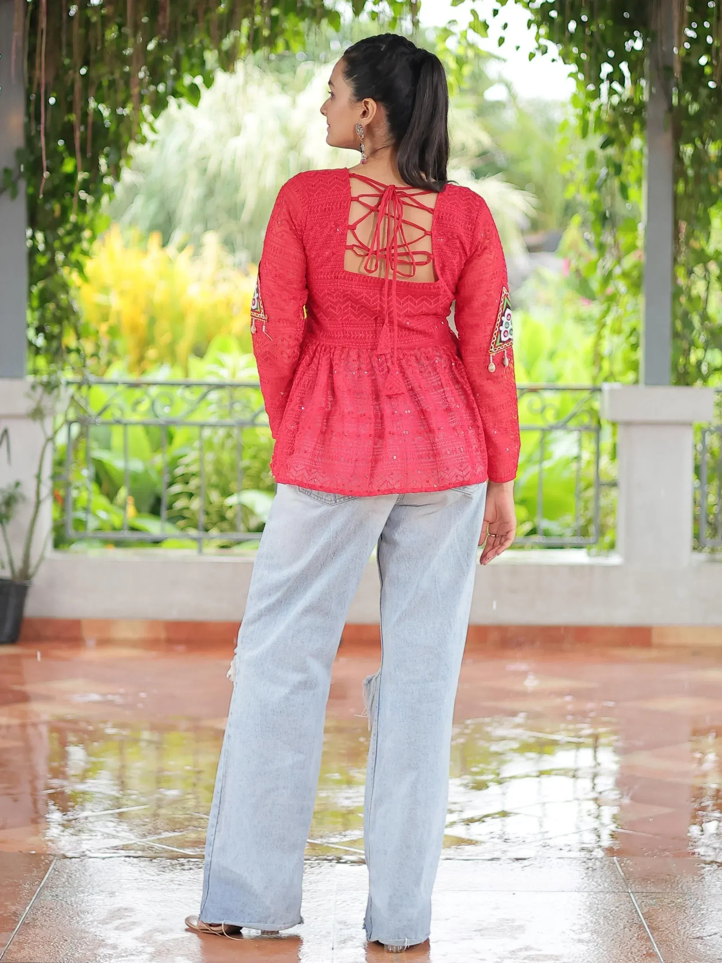 Red ethnic embroidered top with back lace-up detail, paired with wide-leg jeans, perfect for casual Indian wear.