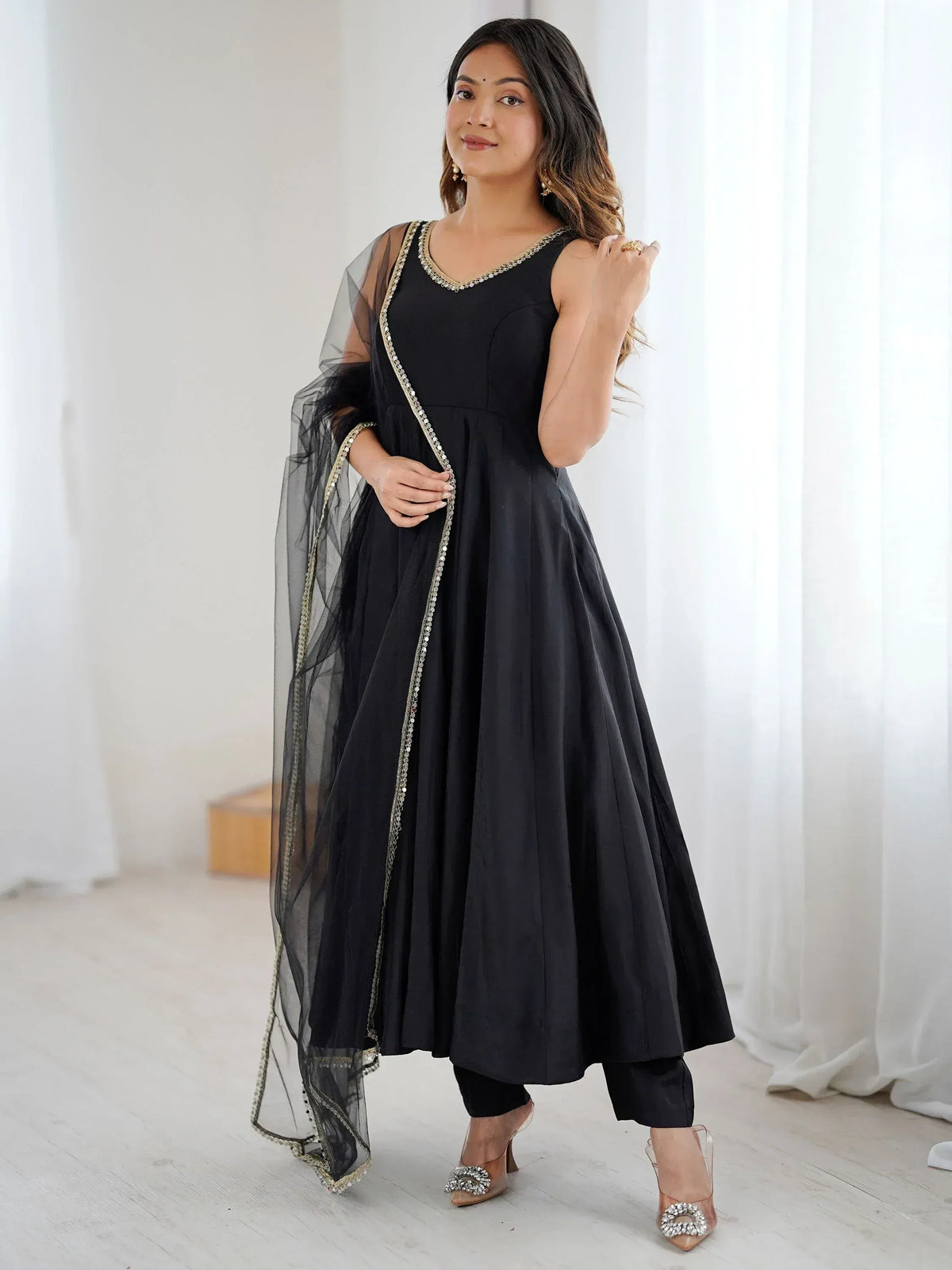Black ethnic gown with gold embroidery and sheer dupatta, paired with embellished heels
