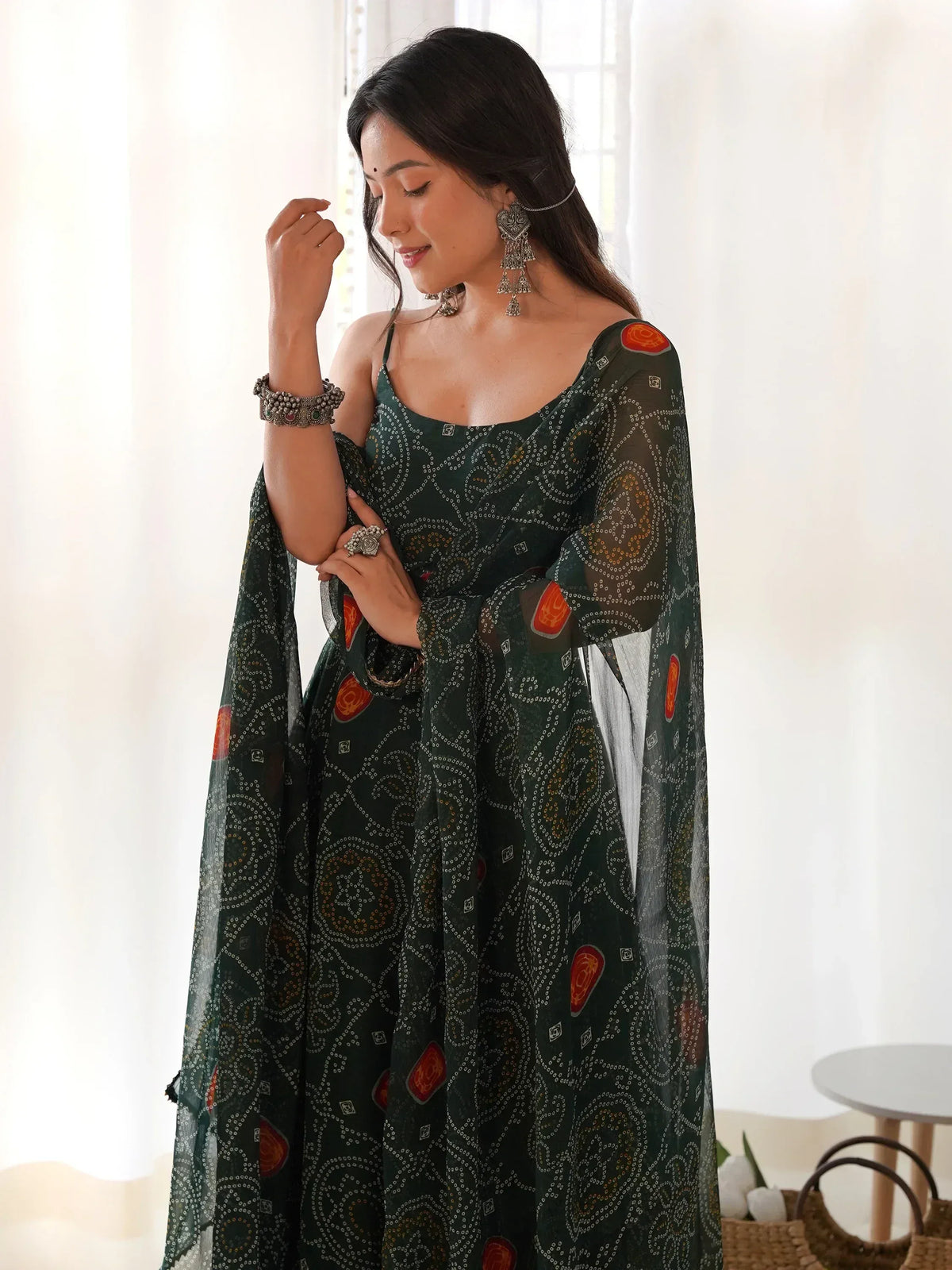 Elegant green ethnic gown with intricate paisley patterns and orange accents, paired with traditional jewelry.