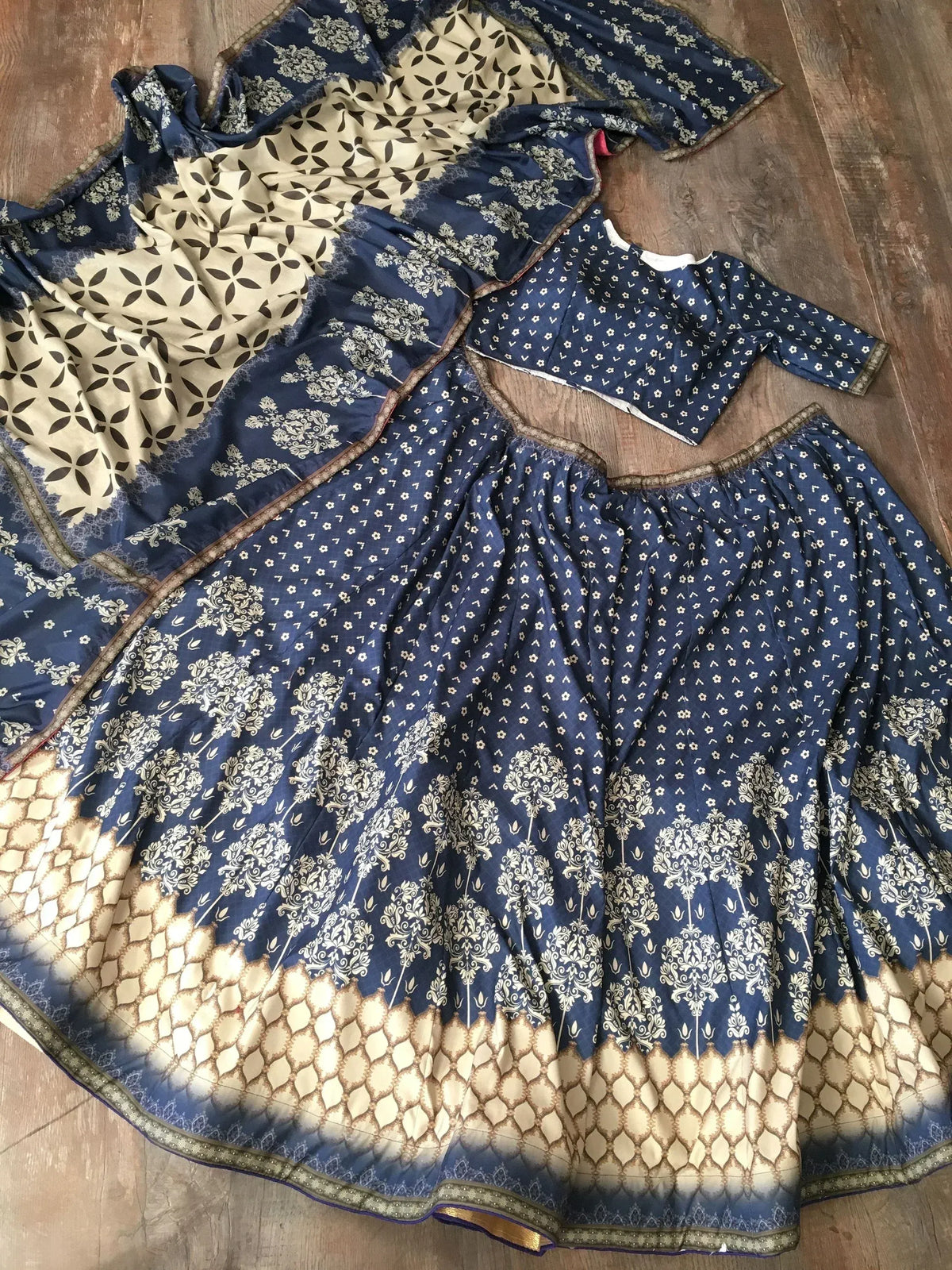 Blue and cream printed Indian ethnic lehenga choli with floral and geometric patterns, laid flat on wood