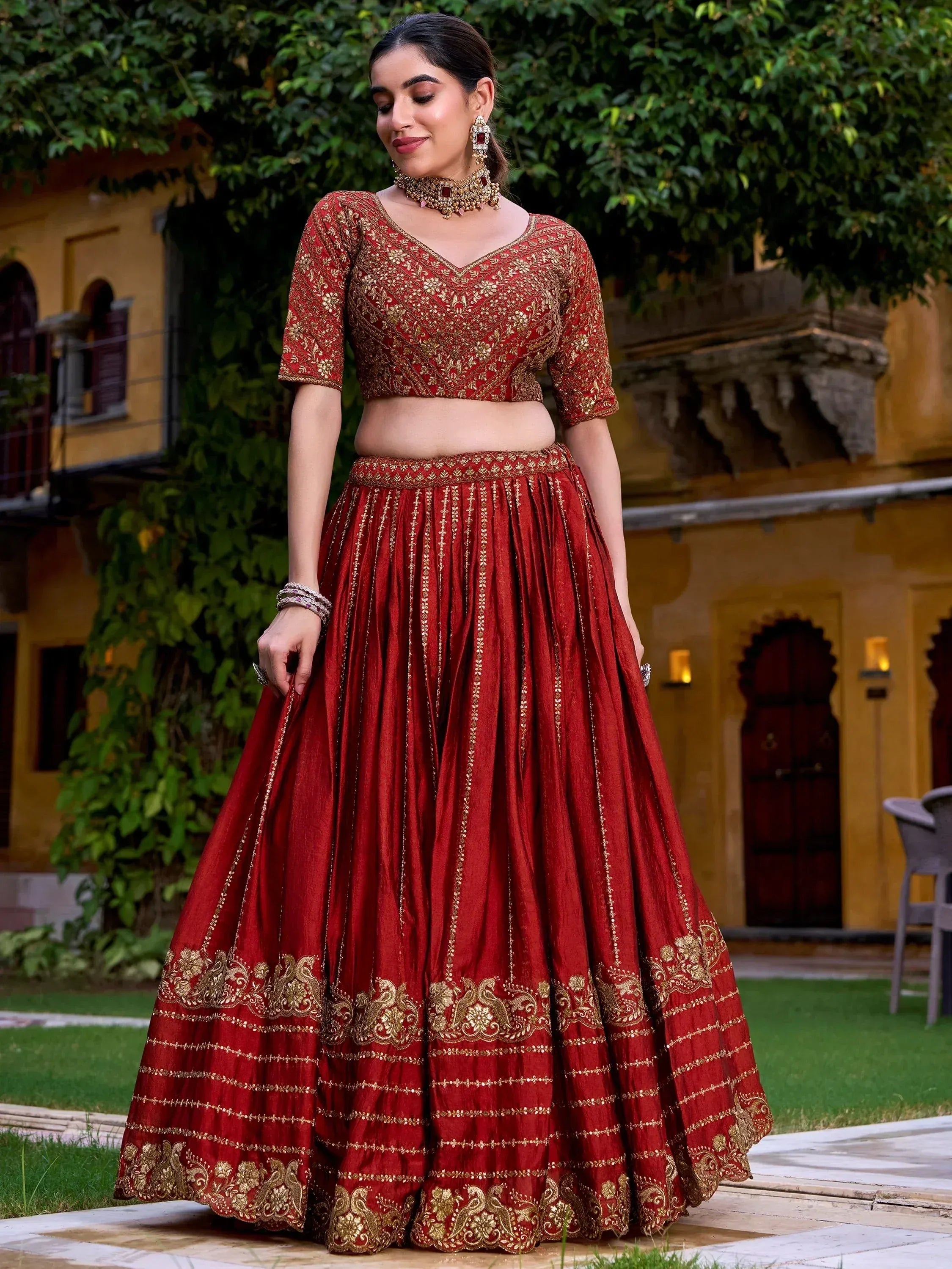 Red and gold embroidered lehenga choli for Indian weddings, featuring intricate zari work and traditional jewelry.