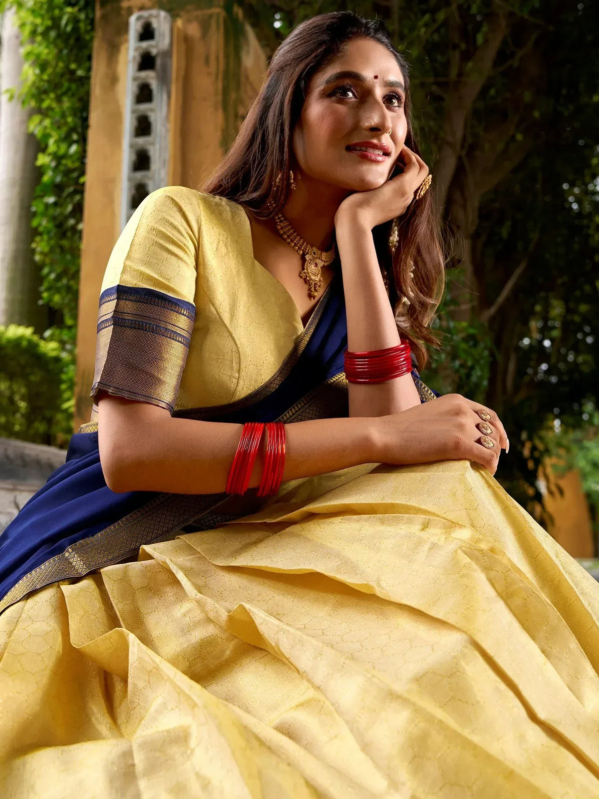 Woman in elegant yellow and navy blue saree with gold jewelry, perfect for Indian ethnic occasions
