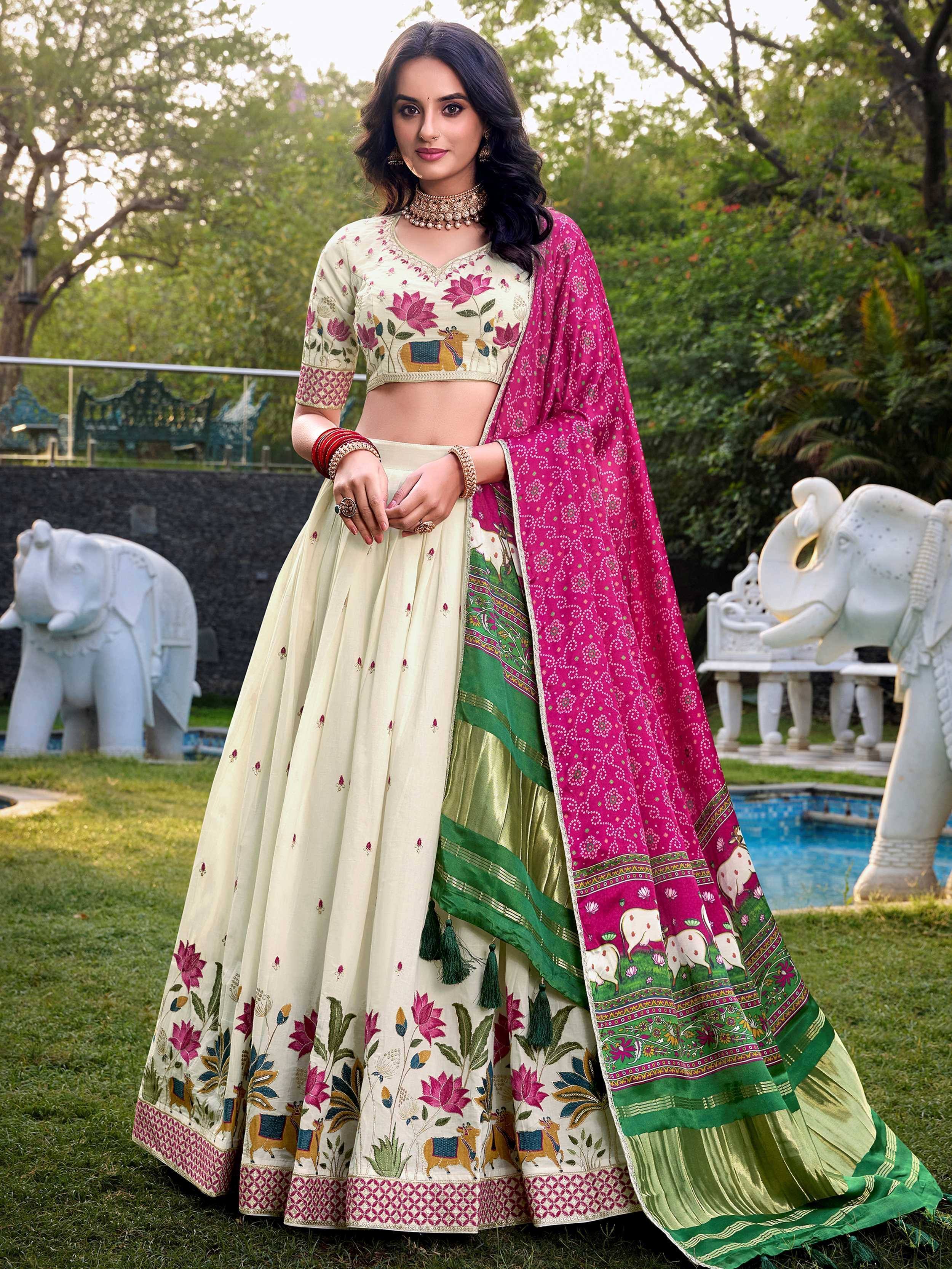 Elegant cream lehenga choli with floral and elephant embroidery, paired with a vibrant pink dupatta.