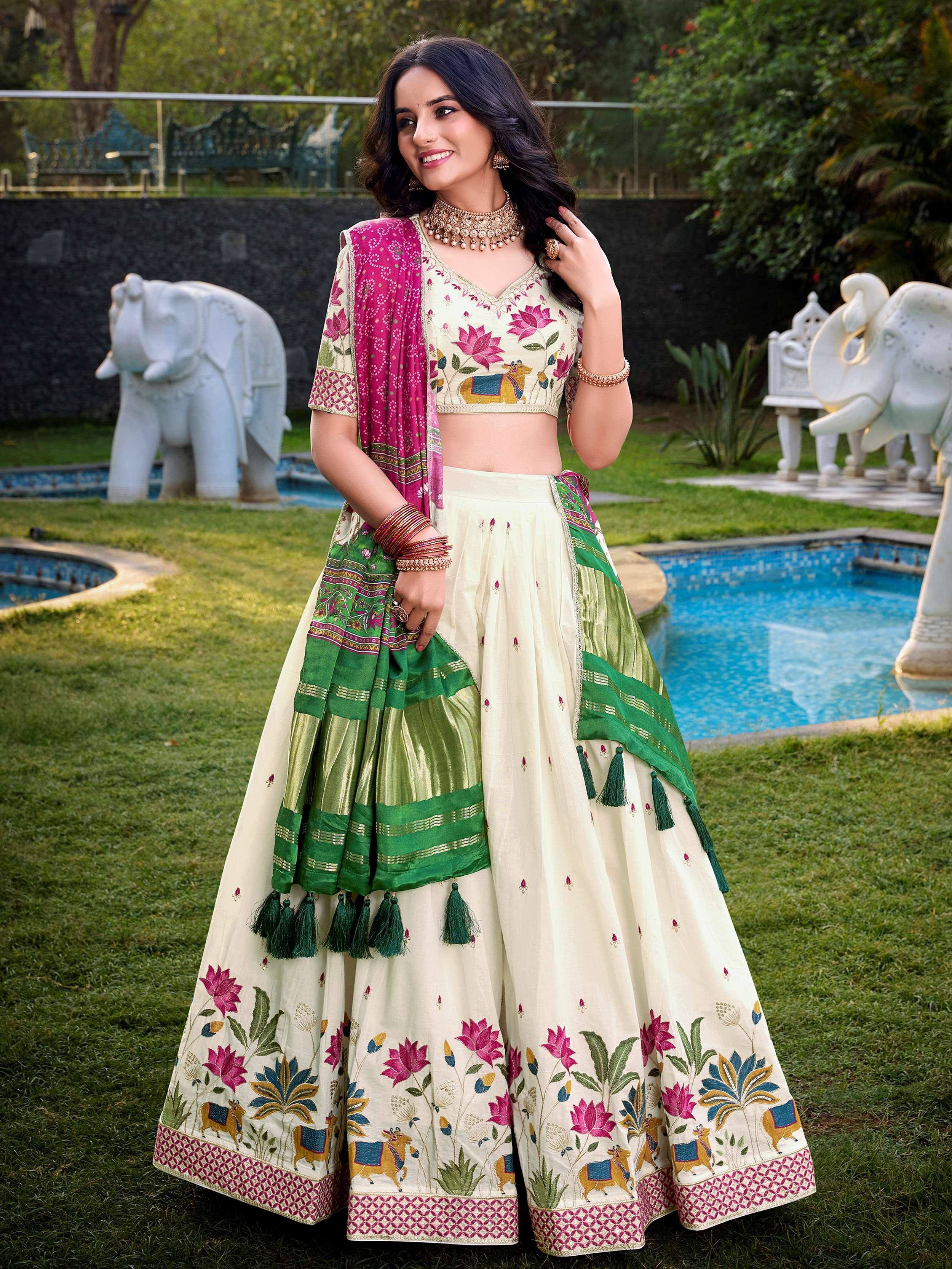 Woman in cream floral embroidered lehenga choli with pink and green dupatta, garden setting