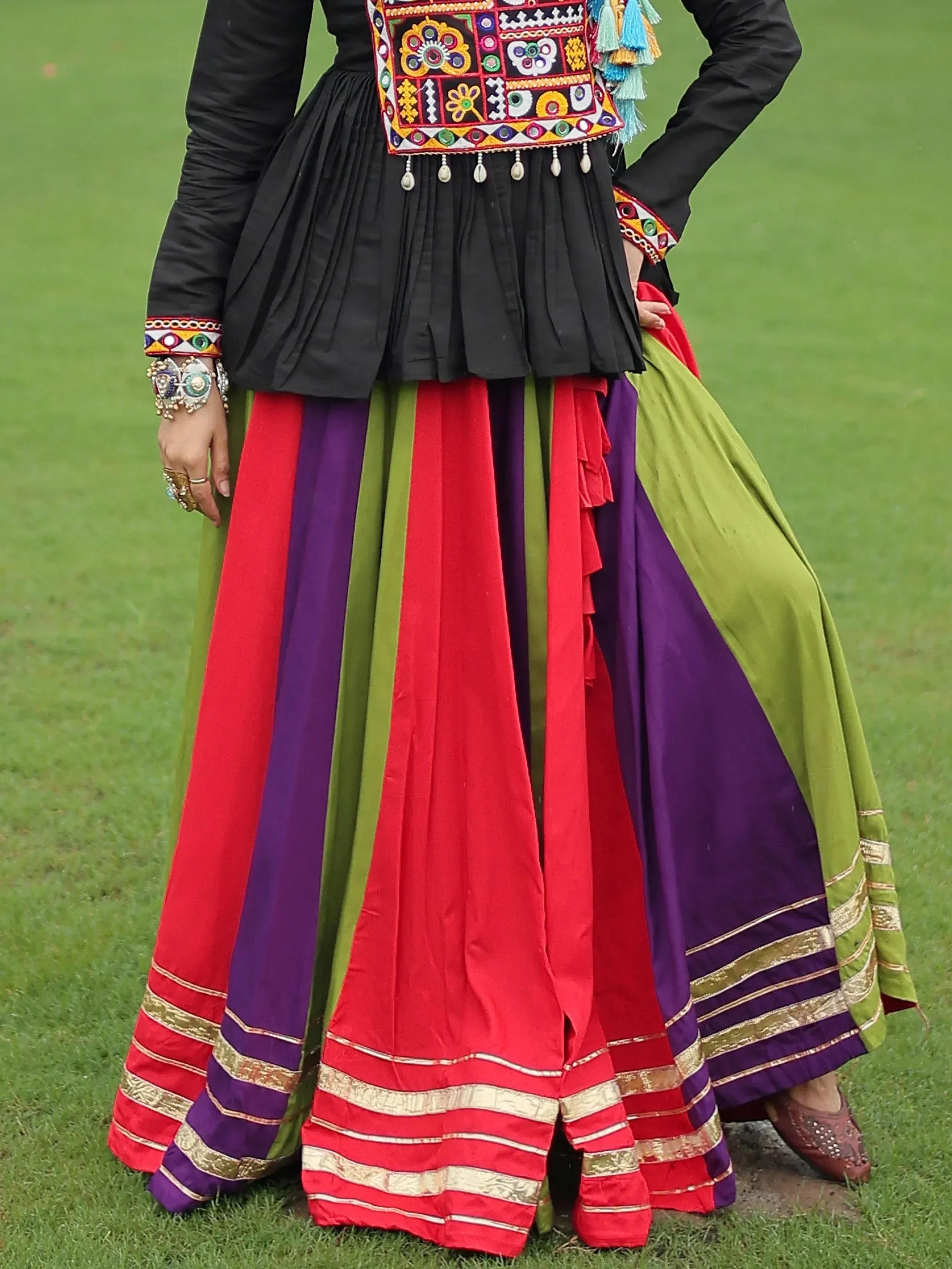 Colorful ethnic skirt with red, purple, green panels and gold trim, paired with black embroidered top