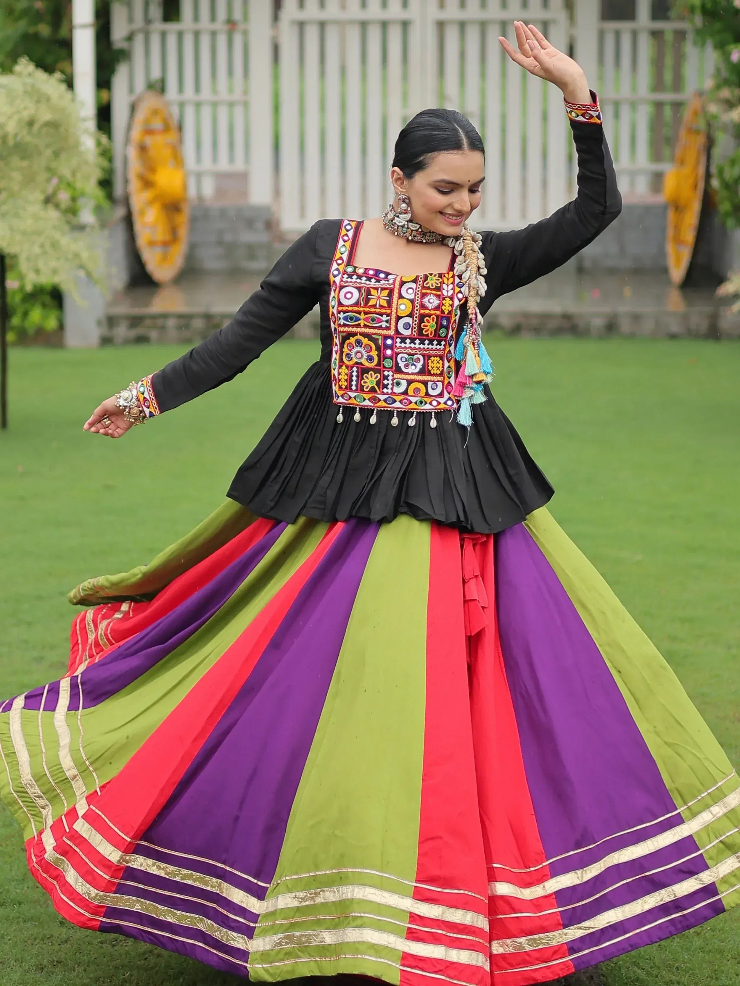 Woman in colorful ethnic Indian dress with embroidered top and pleated skirt, dancing outdoors
