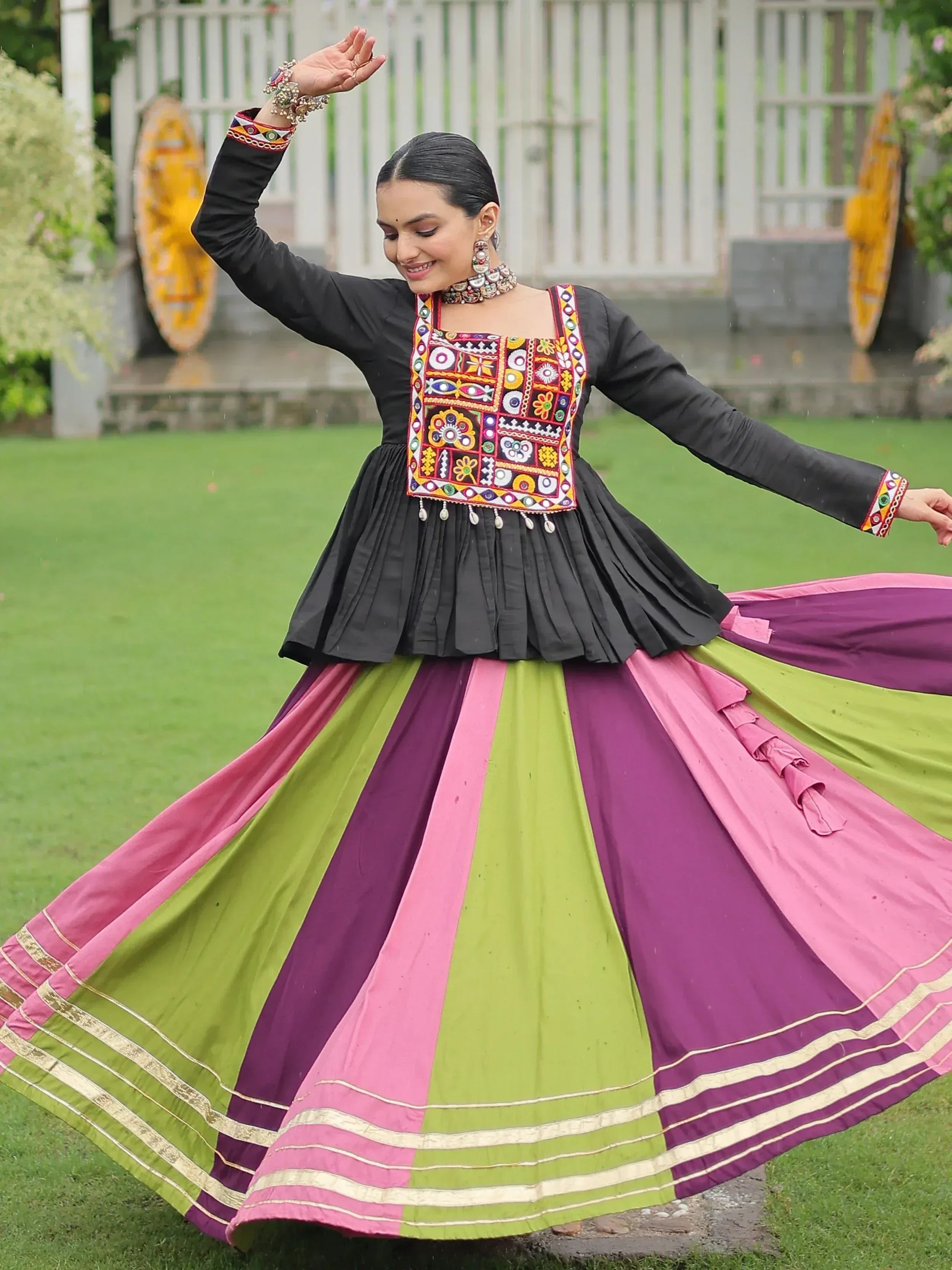 Woman twirling in colorful ethnic gown with embroidered black top and vibrant skirt