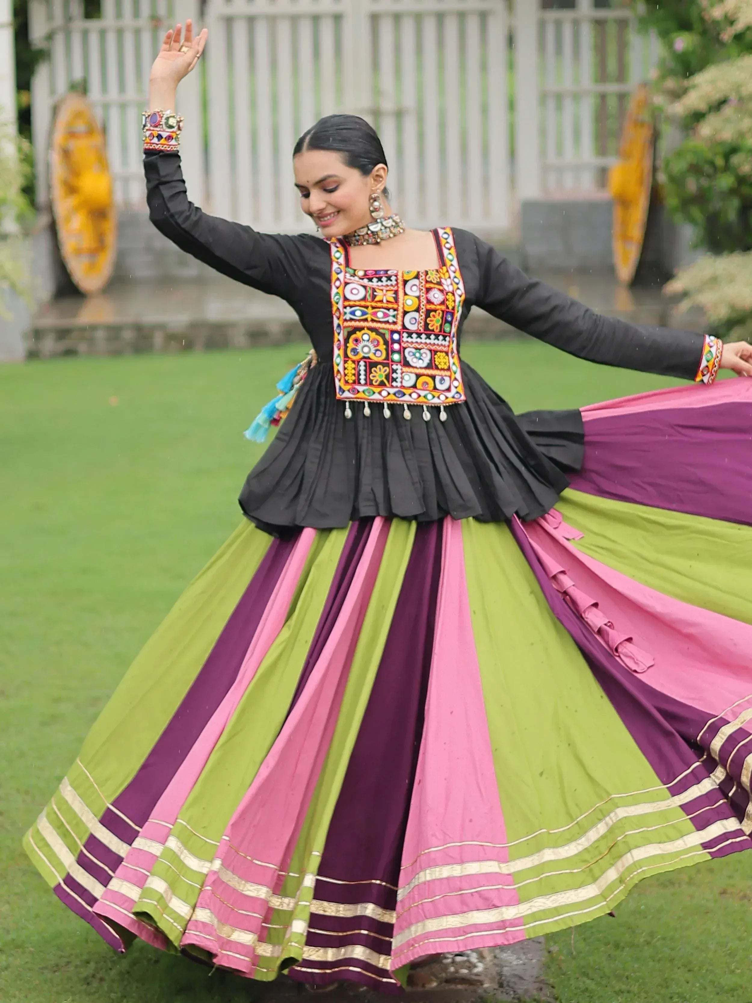 Woman twirling in colorful Indian ethnic wear with embroidered black top and striped skirt