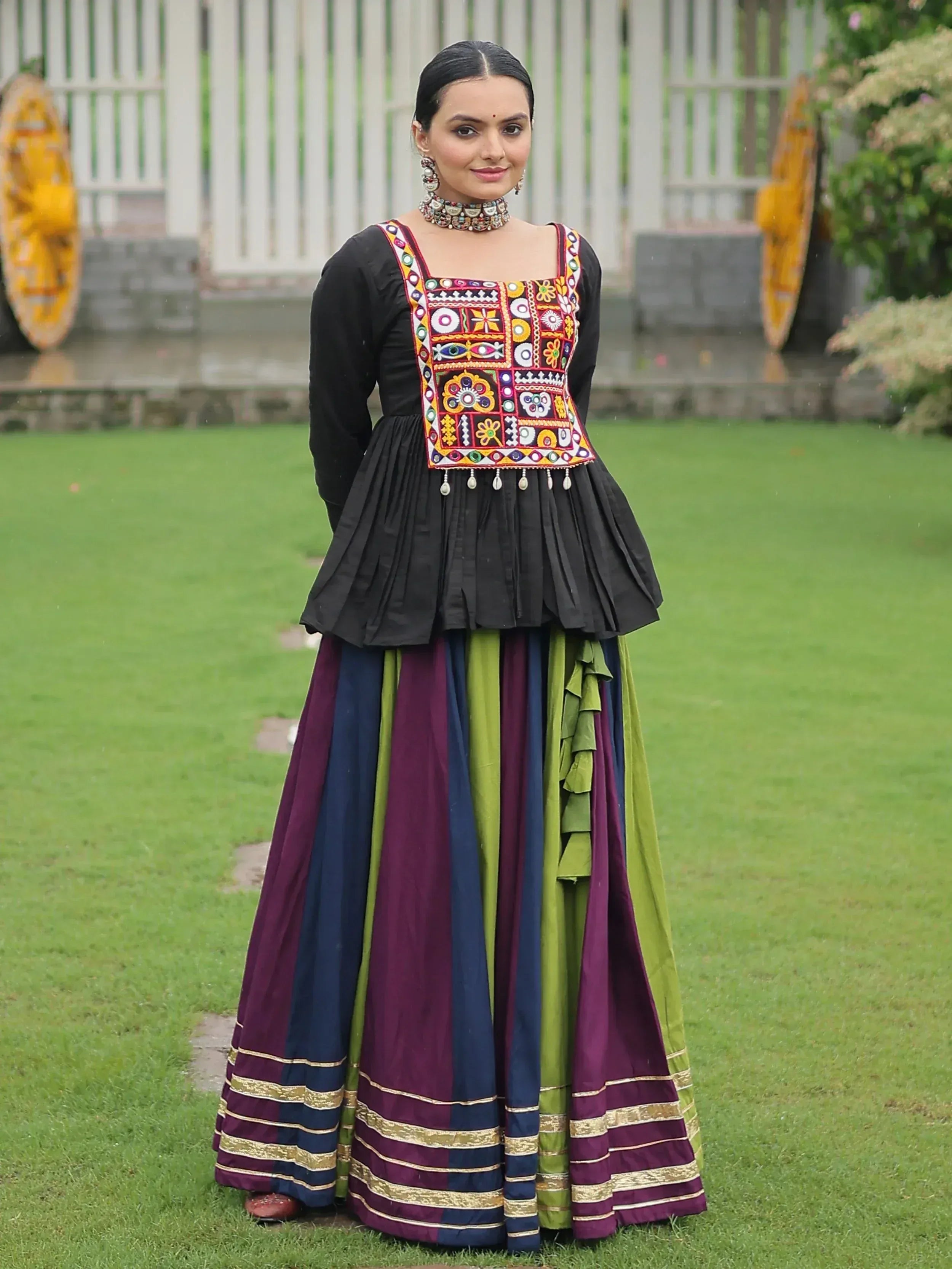 Woman in colorful embroidered ethnic gown with pleated black top and striped skirt