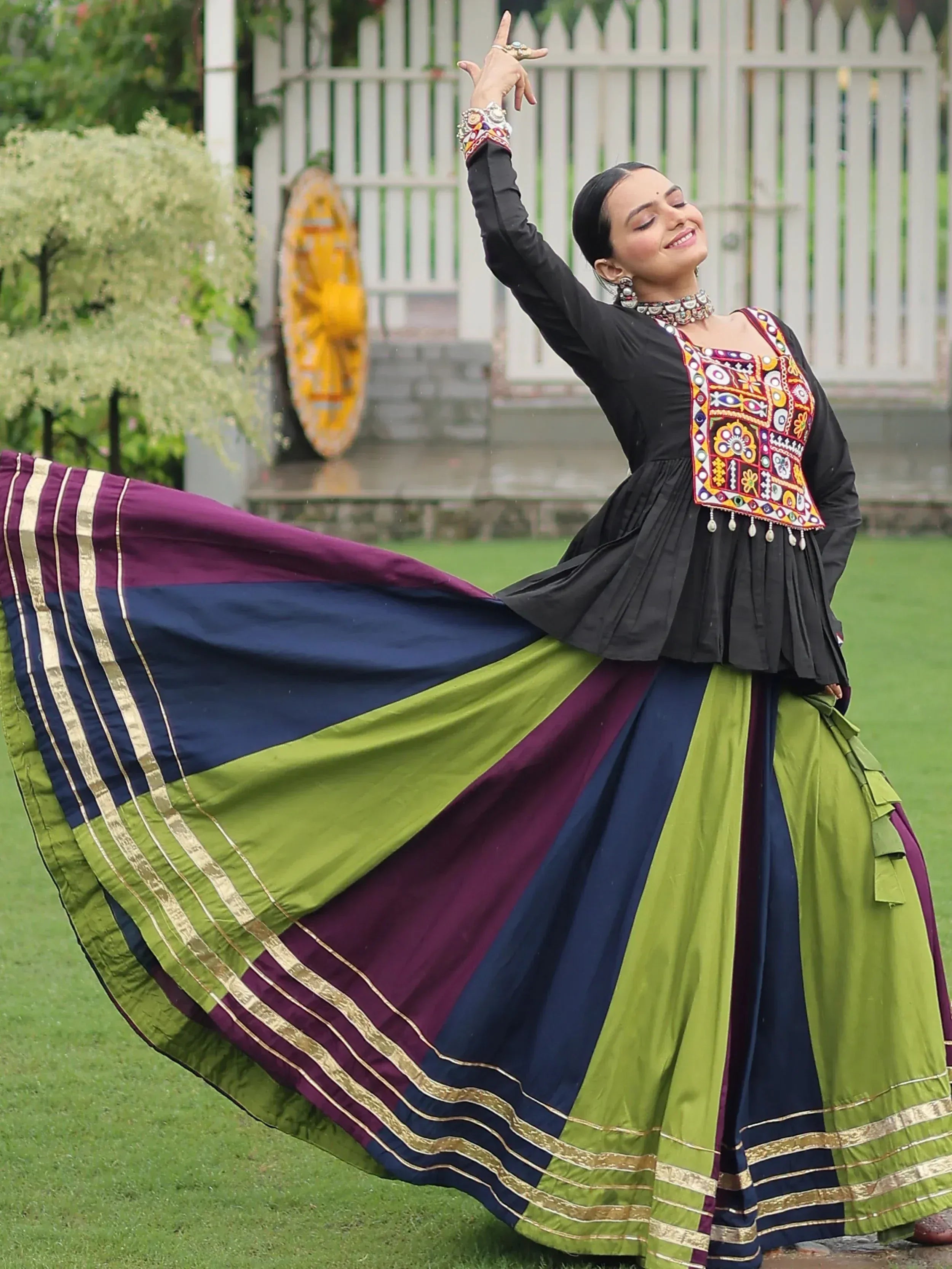 Woman dancing in colorful Indian ethnic wear with embroidered top and pleated skirt, perfect for festive occasions.