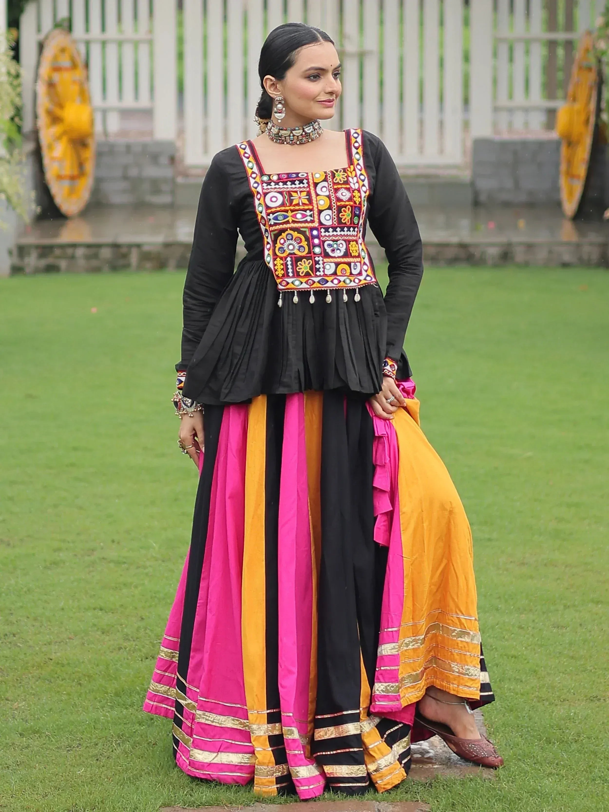 Woman in black embroidered top with colorful striped skirt, traditional Indian ethnic wear