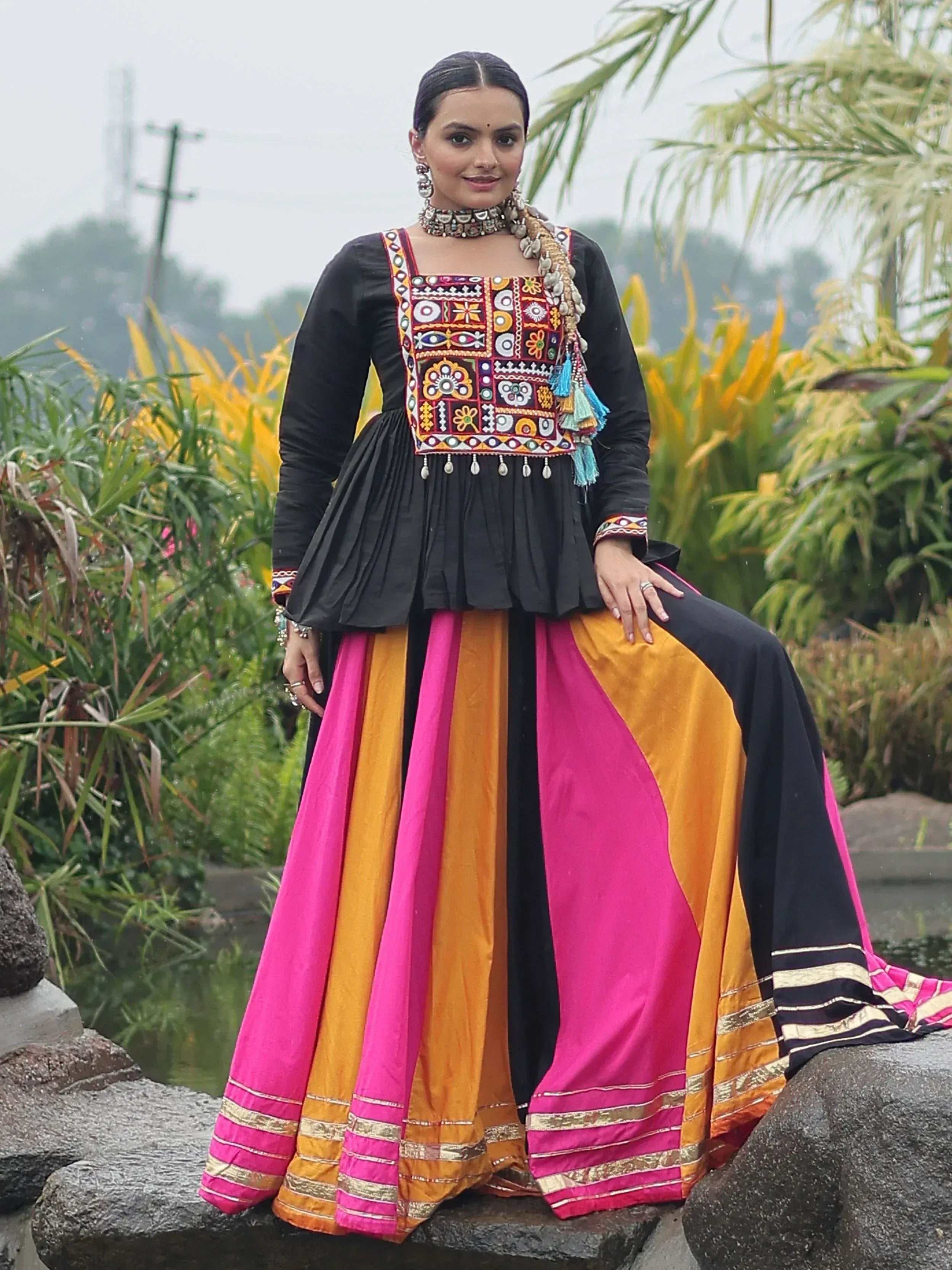 Woman in black embroidered top with vibrant pink and orange lehenga, traditional Indian ethnic wear