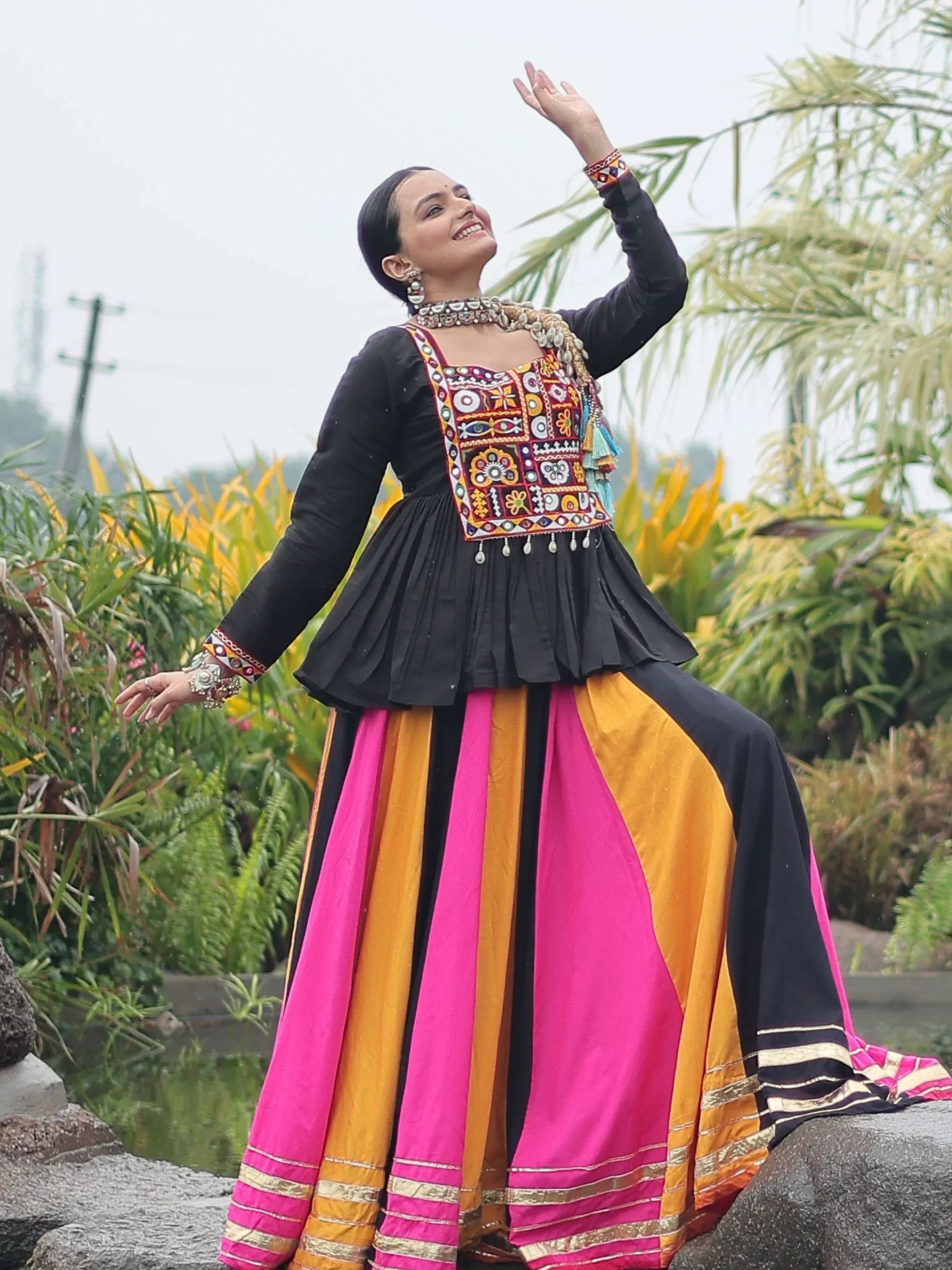 Woman in black embroidered top with colorful pink and orange skirt, traditional Indian ethnic wear