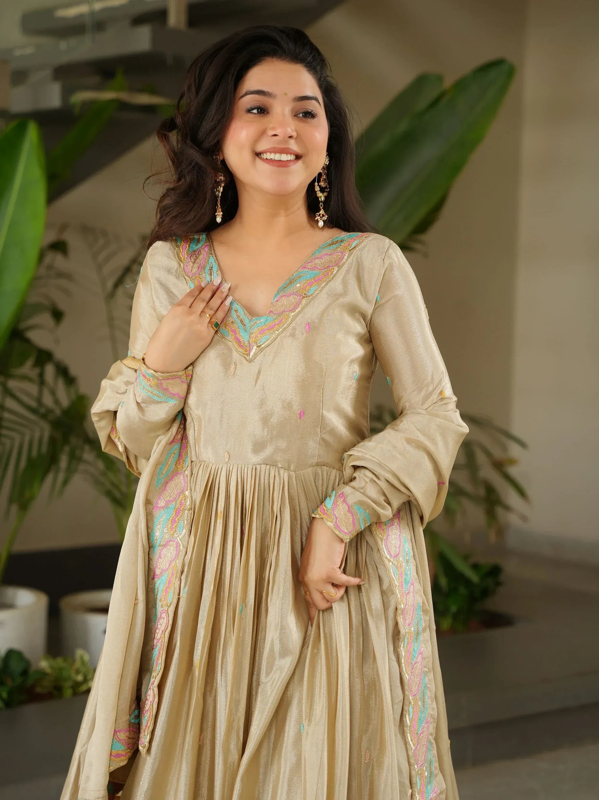 Woman in gold ethnic gown with colorful embroidery, perfect for Indian occasions and festive wear.