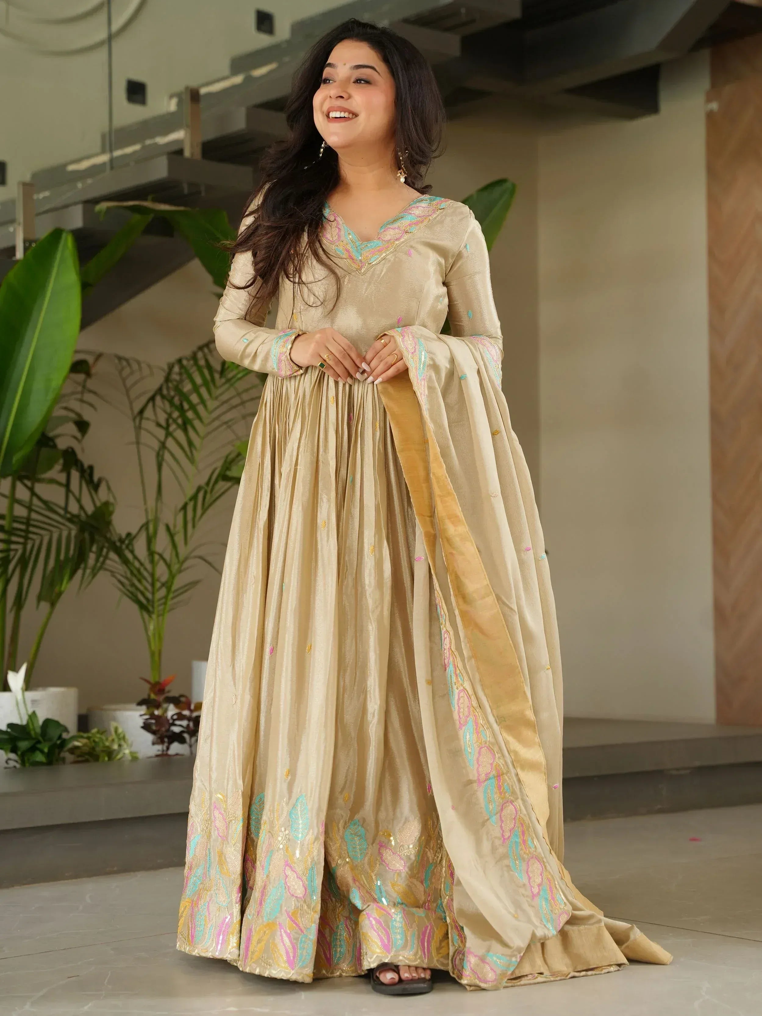 Beige embroidered ethnic gown with colorful floral motifs, perfect for Indian occasions and festive wear.