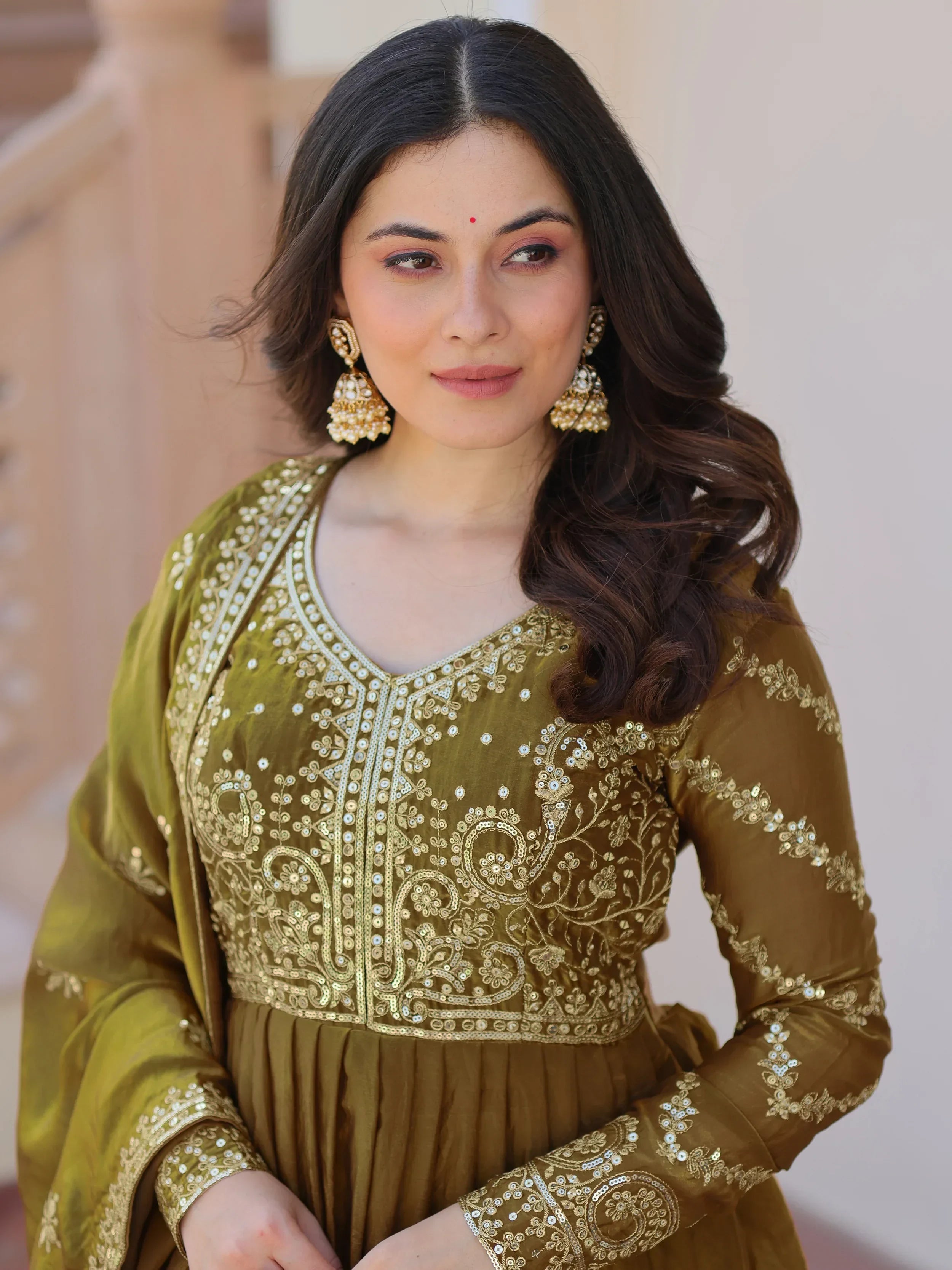 Woman in olive green embroidered anarkali suit with dupatta and gold jhumka earrings