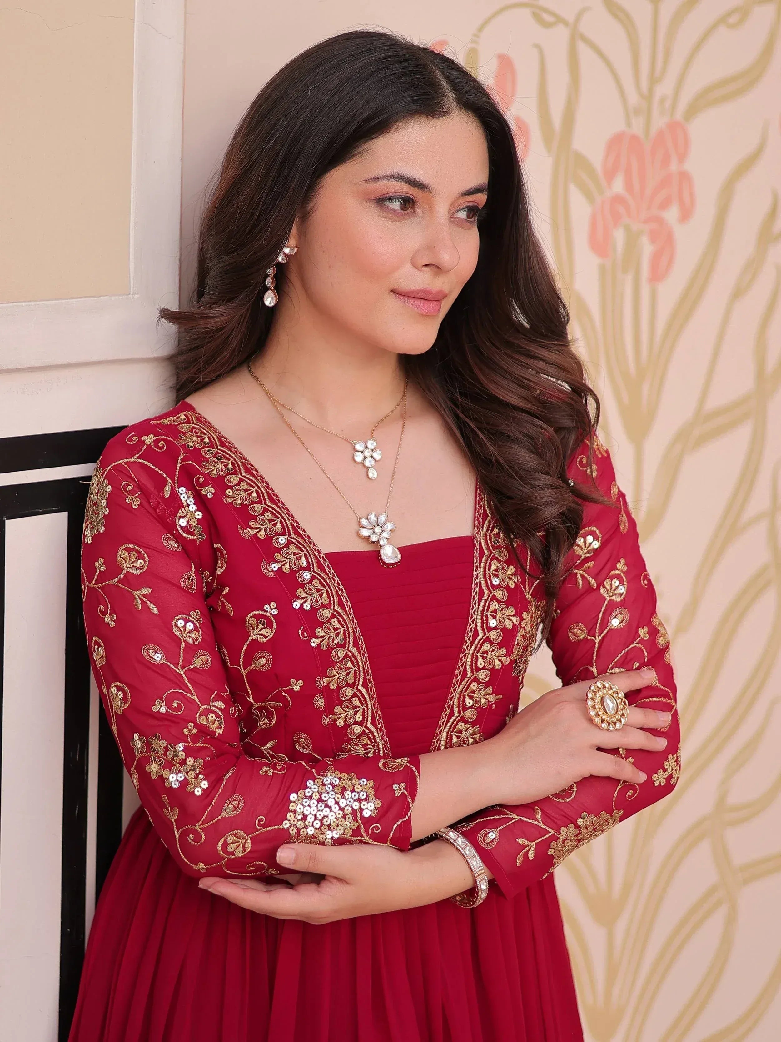 Woman in red ethnic gown with gold embroidery and sequins, paired with traditional jewelry