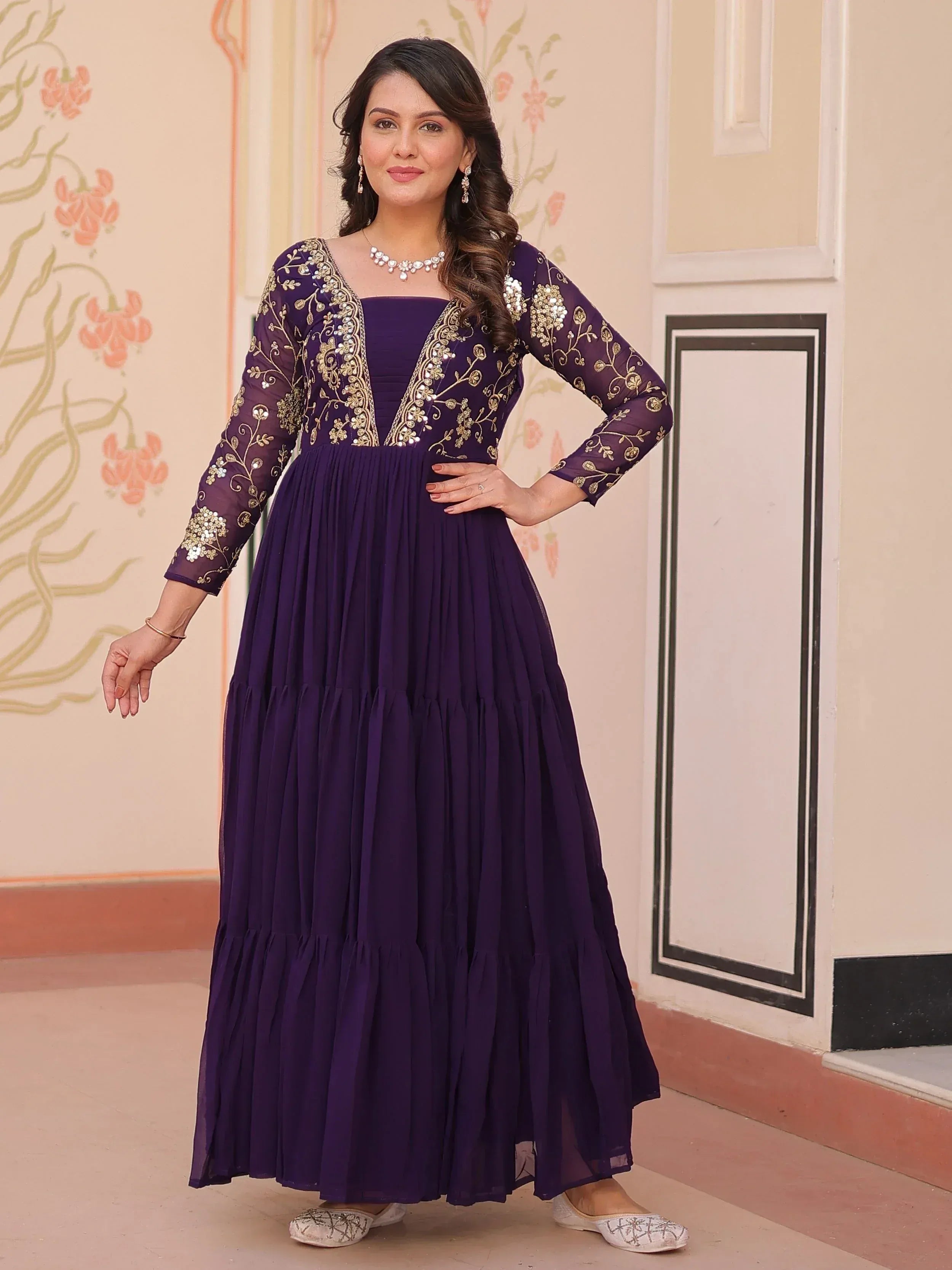 Purple ethnic gown with gold embroidery, pleated skirt, and sheer sleeves for festive occasions