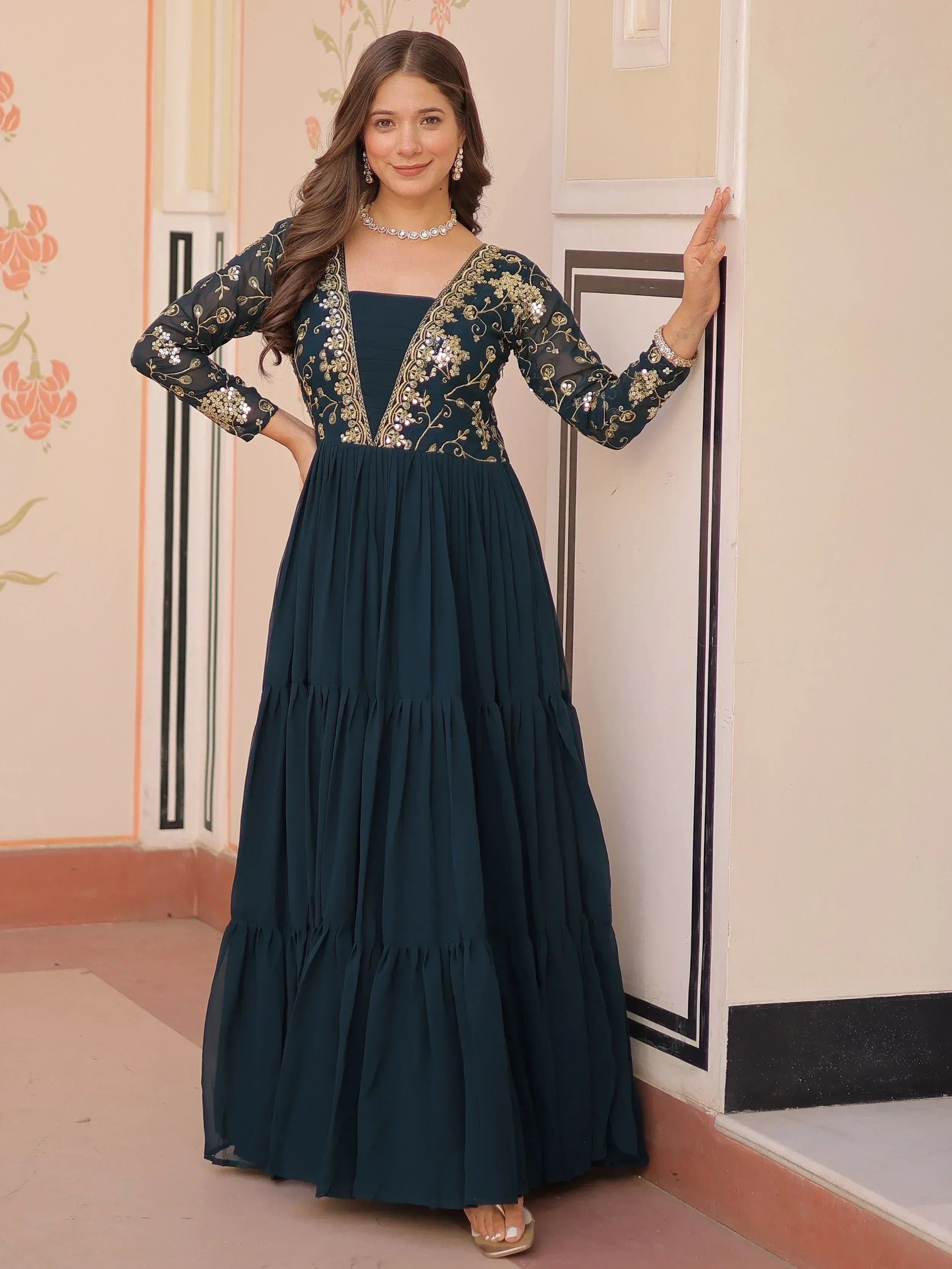 Elegant dark green ethnic gown with gold embroidery and sheer sleeves, perfect for Indian occasions.