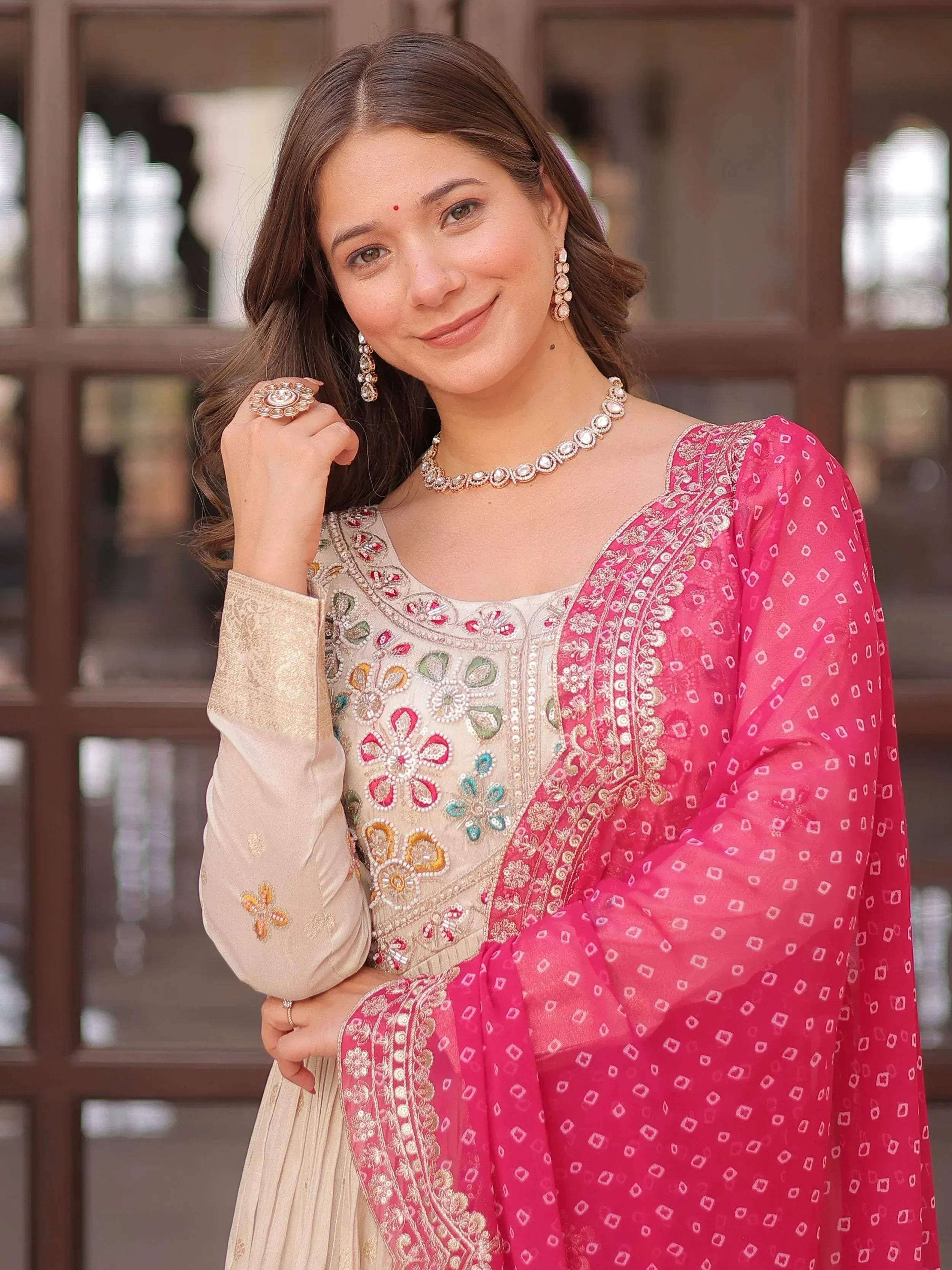 Woman in embroidered beige and pink Indian ethnic wear with matching dupatta and jewelry