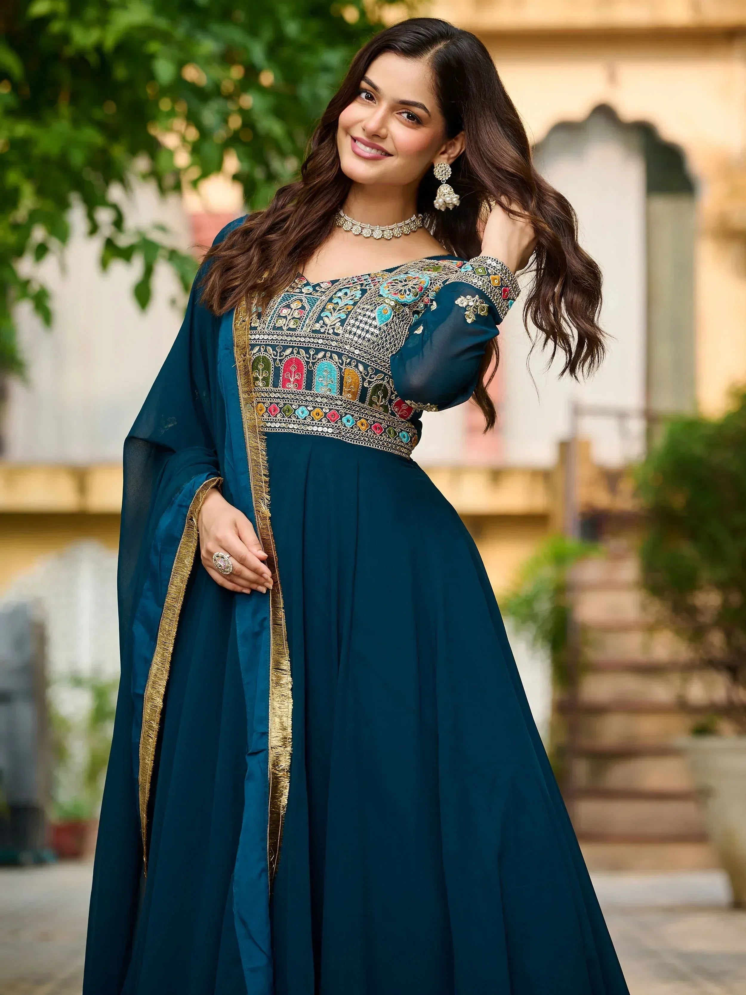 Teal Indian ethnic gown with colorful embroidery and gold trim, perfect for festive occasions.