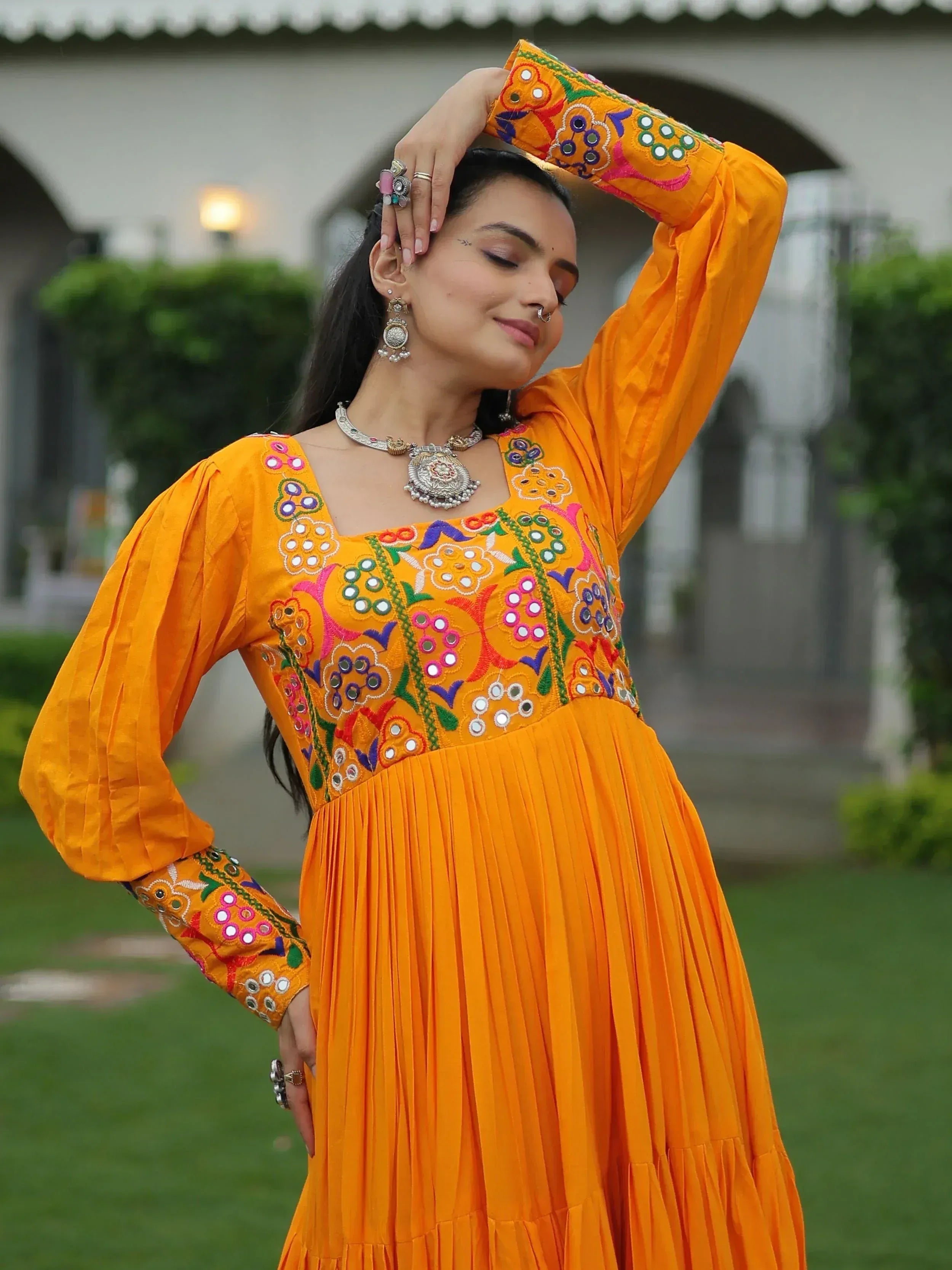 Vibrant orange ethnic gown with mirror work and floral embroidery, perfect for Indian festive wear.