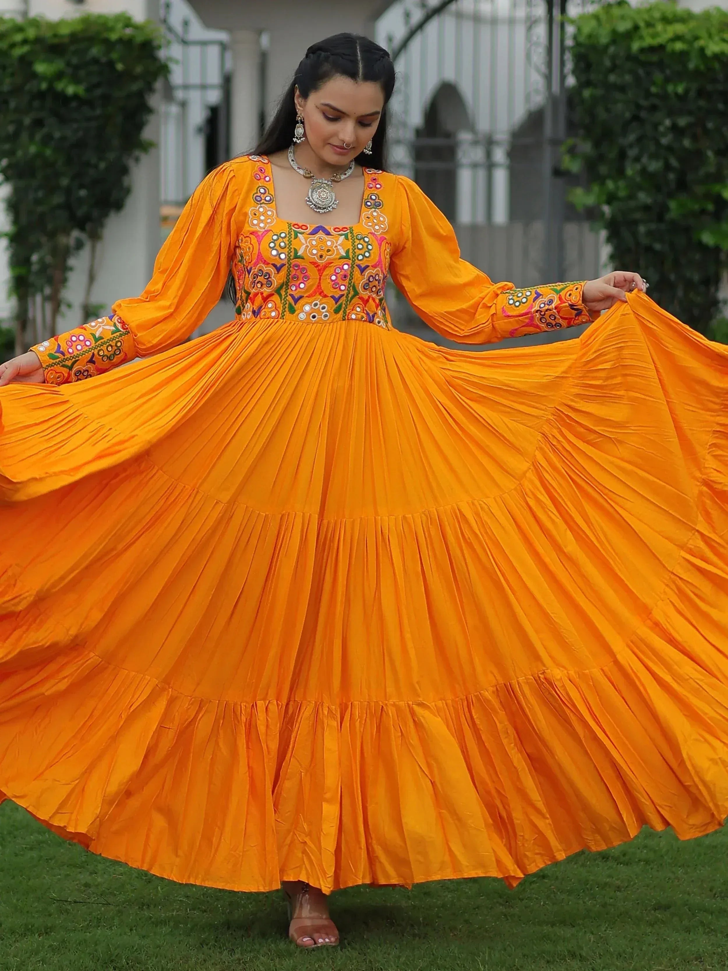 Vibrant orange ethnic gown with mirror work, perfect for Indian celebrations and festive occasions.