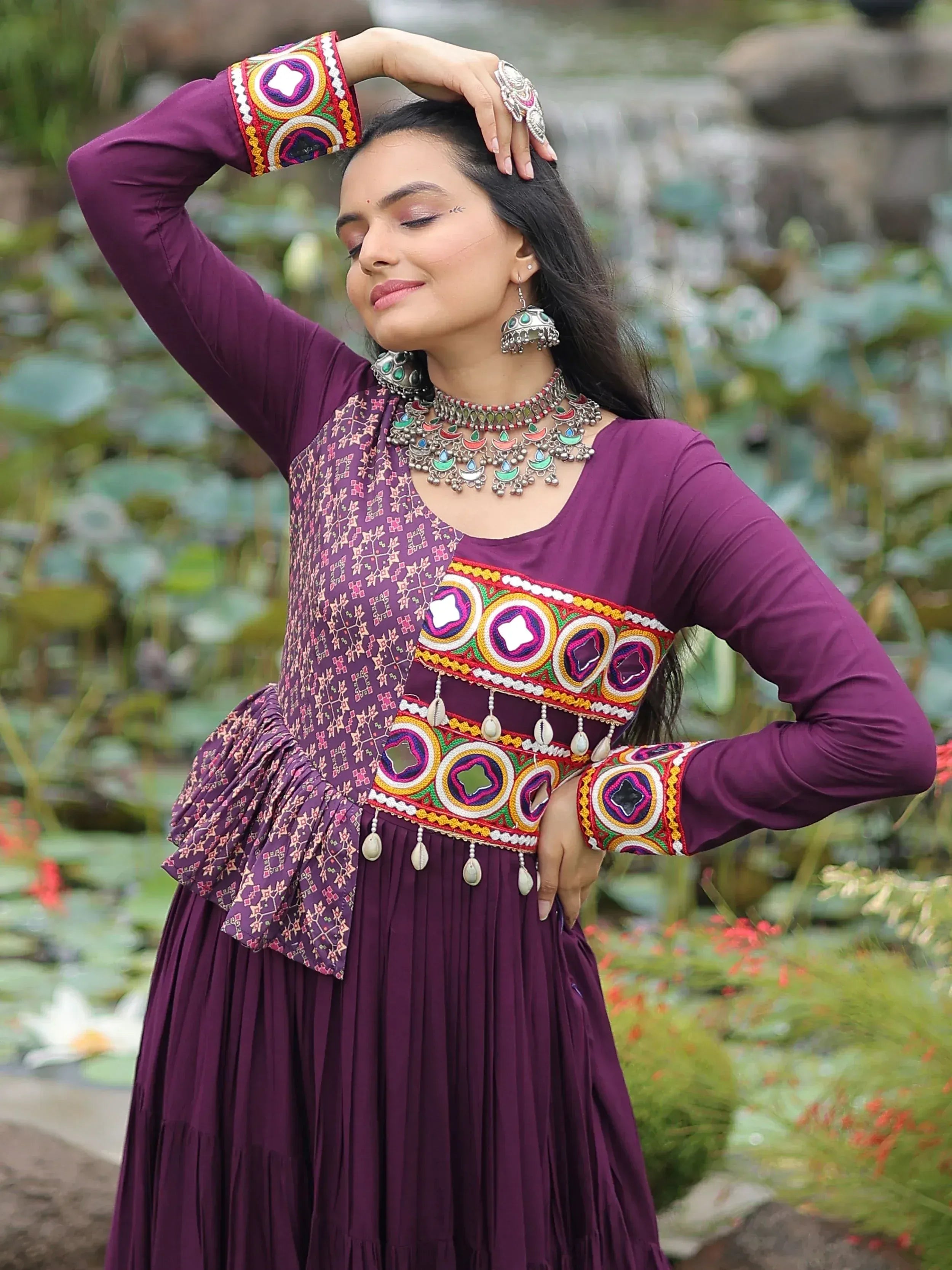 Woman in purple ethnic gown with mirror work and embroidery, styled with traditional jewelry