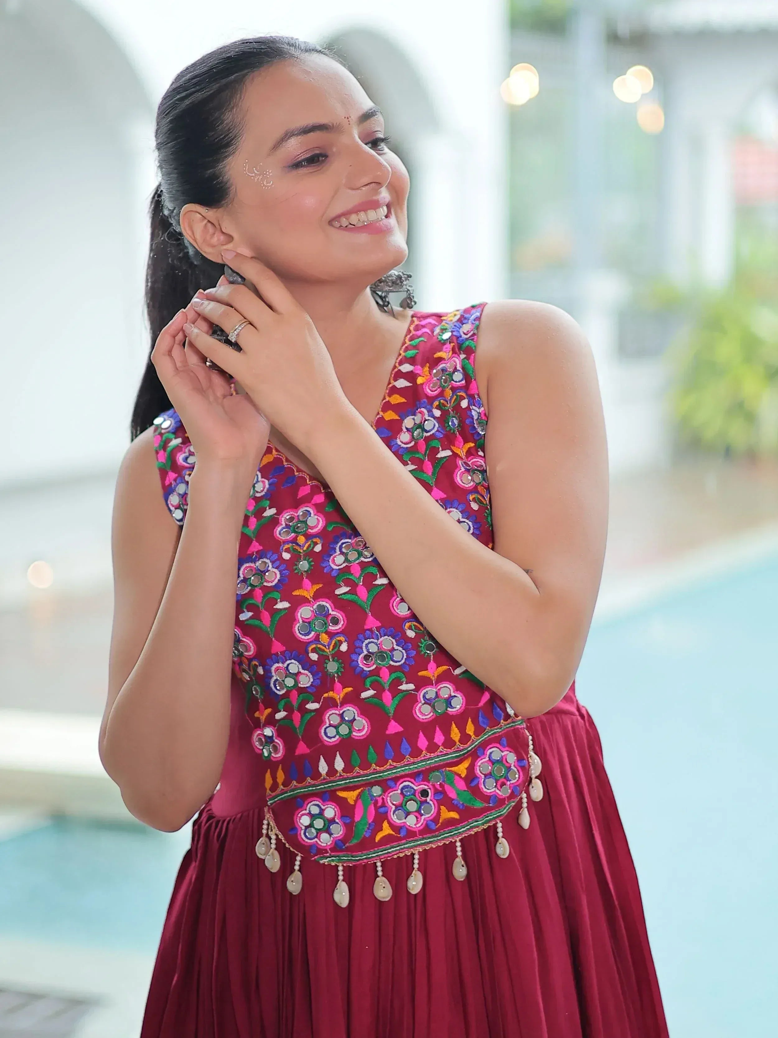 Woman in maroon ethnic gown with mirror embroidery, perfect for Indian festive occasions