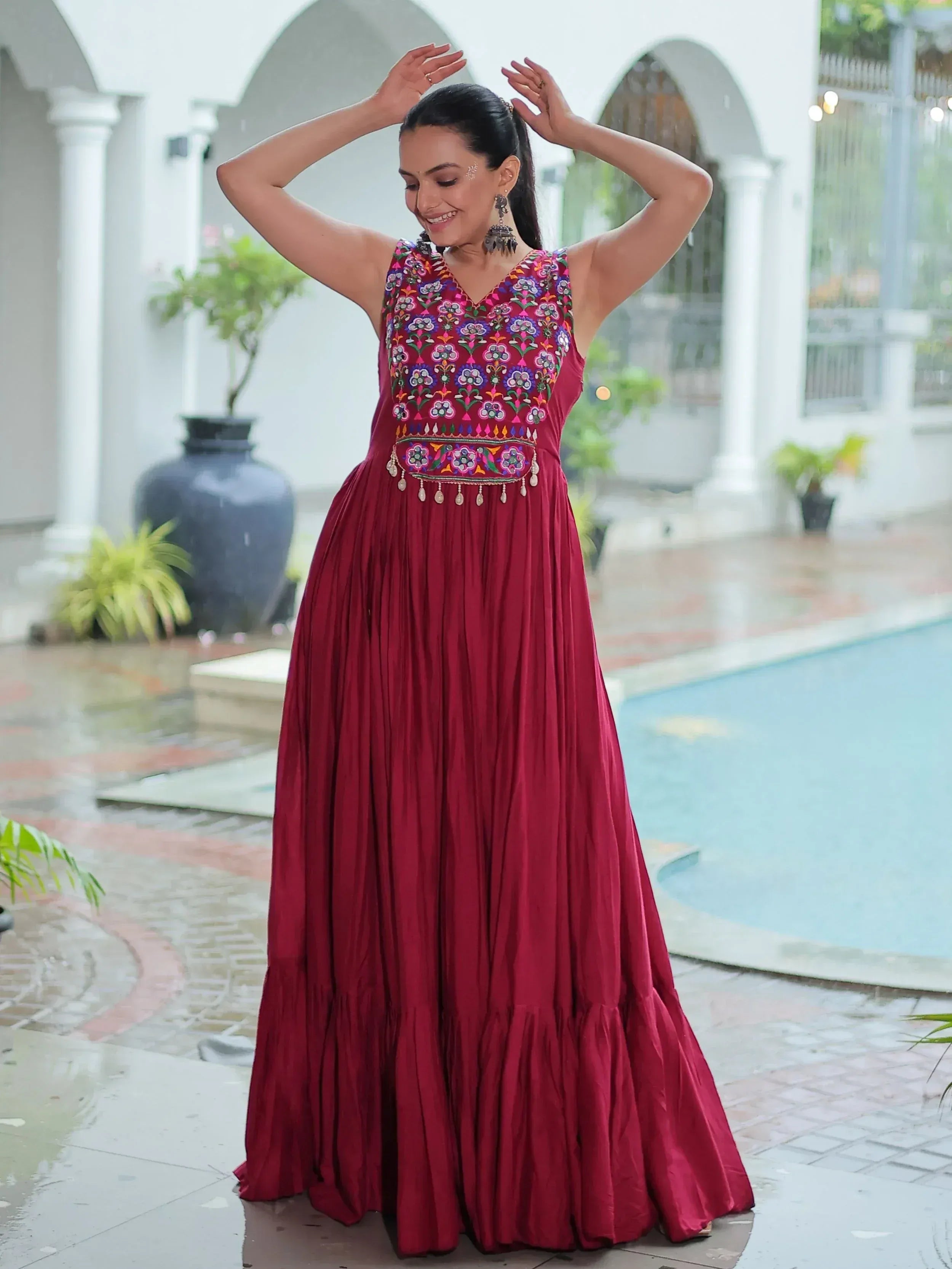 Woman in maroon embroidered ethnic gown with floral motifs, perfect for Indian occasions and festive wear.